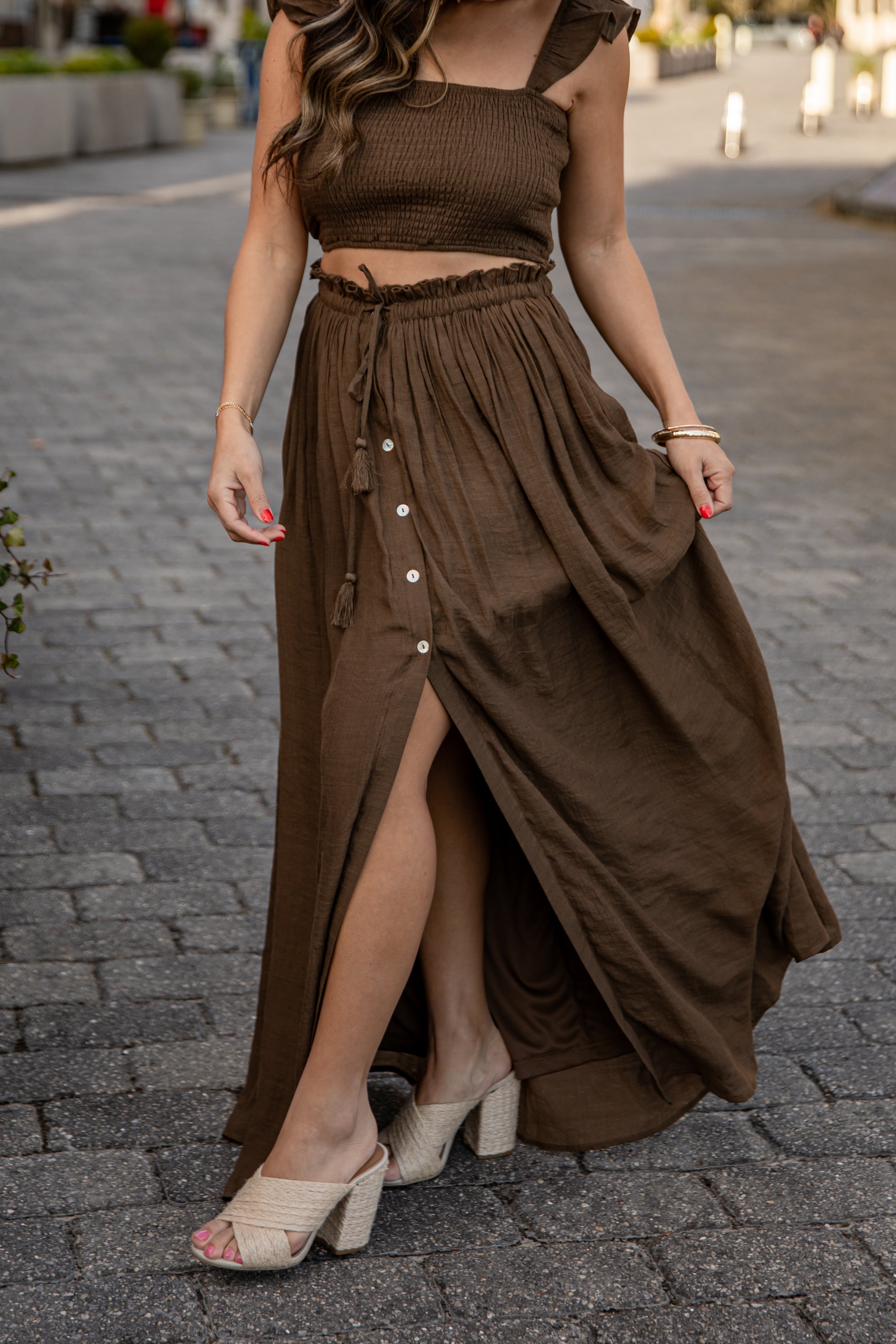 Woman wearing a brown outfit with a skirt on a street.