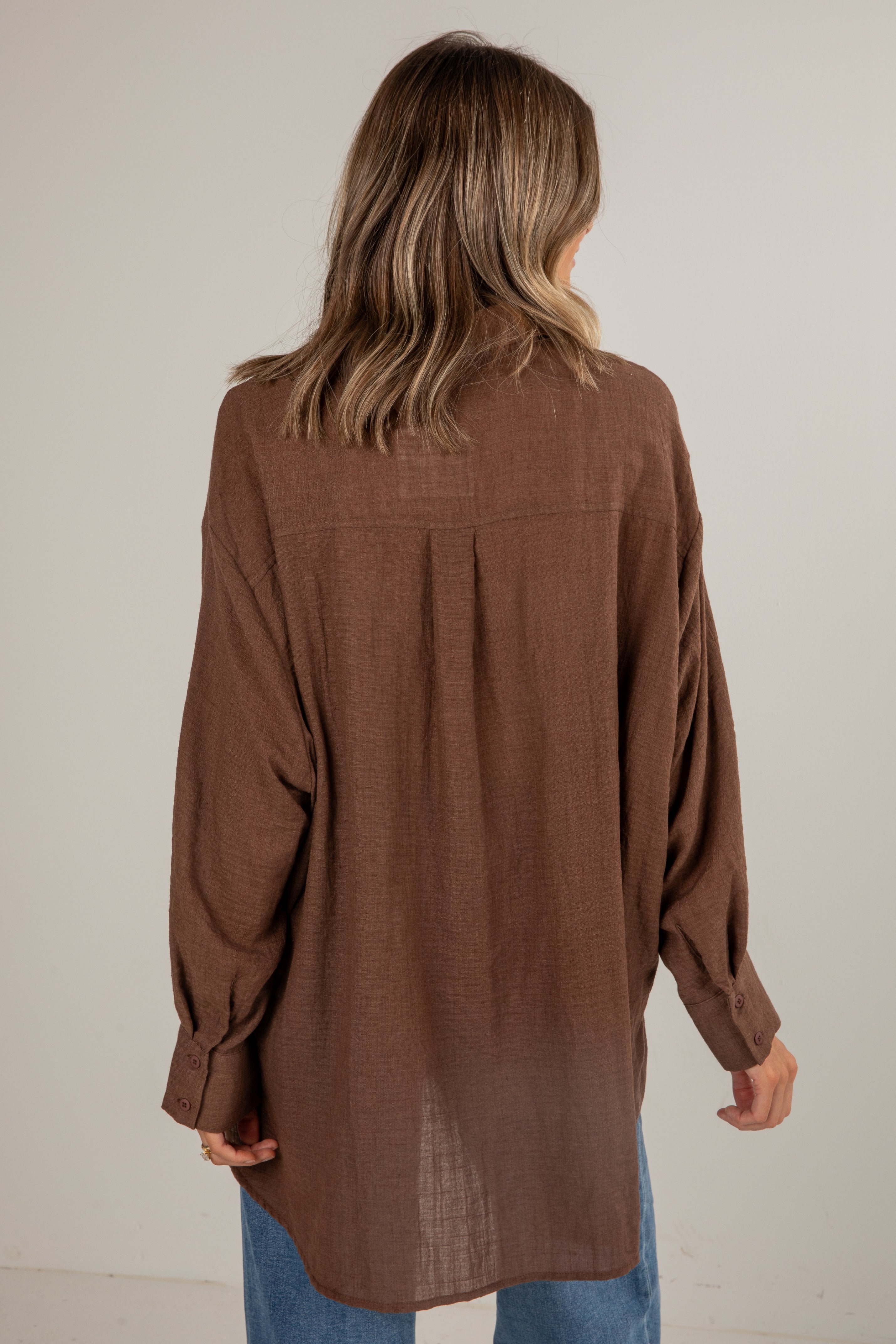 Brown long-sleeve shirt worn by a person on a plain background