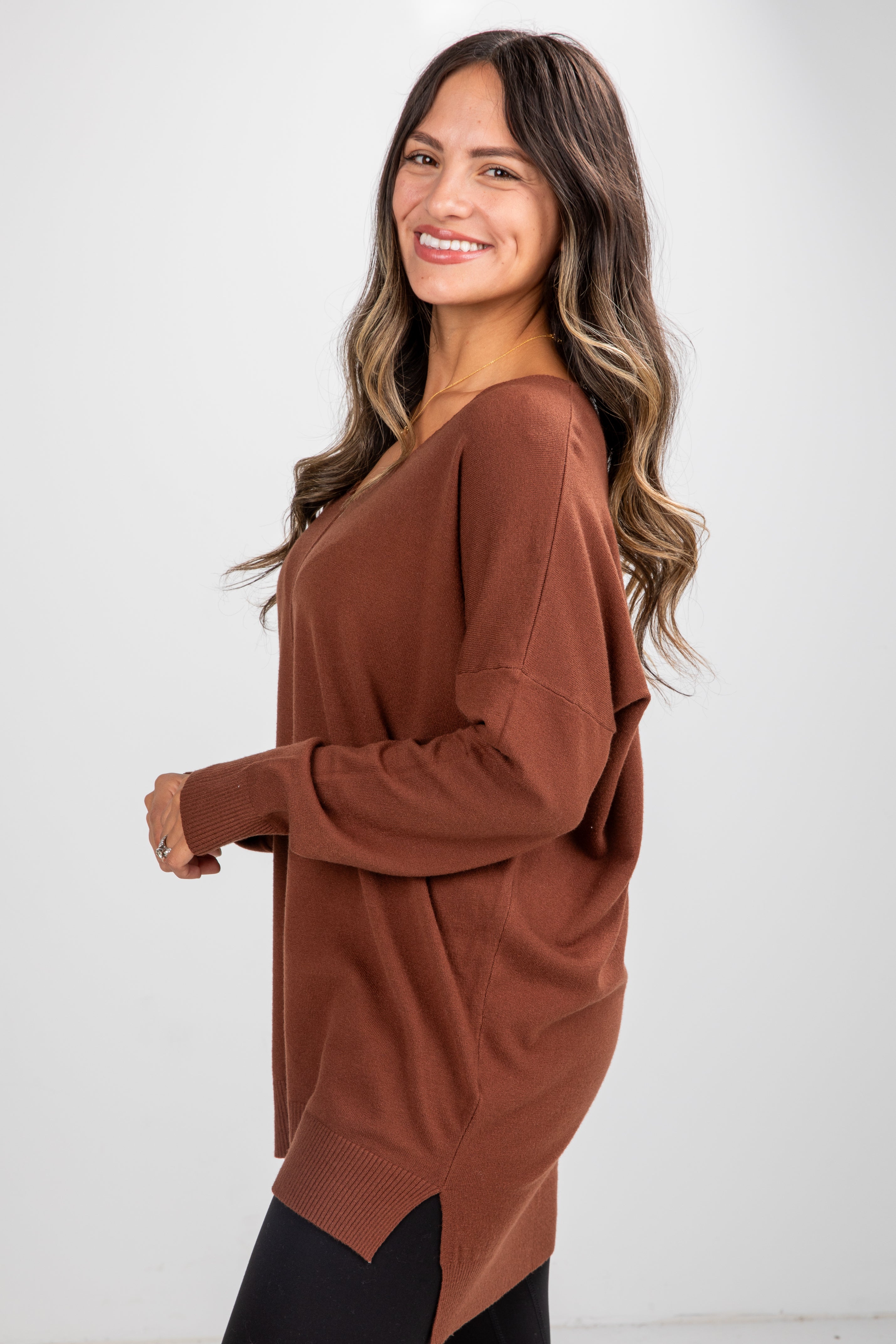 Woman wearing a brown long-sleeve top against a white background