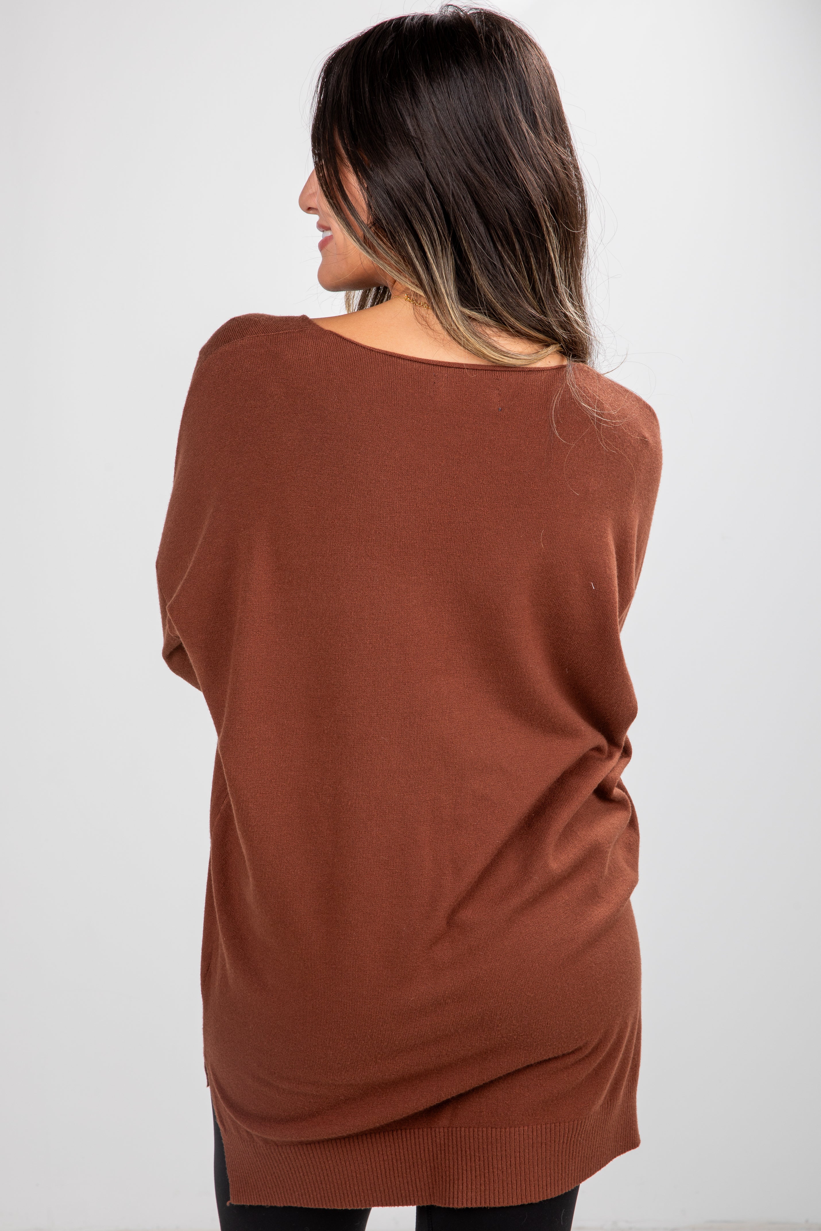 Woman wearing a brown sweater against a white background