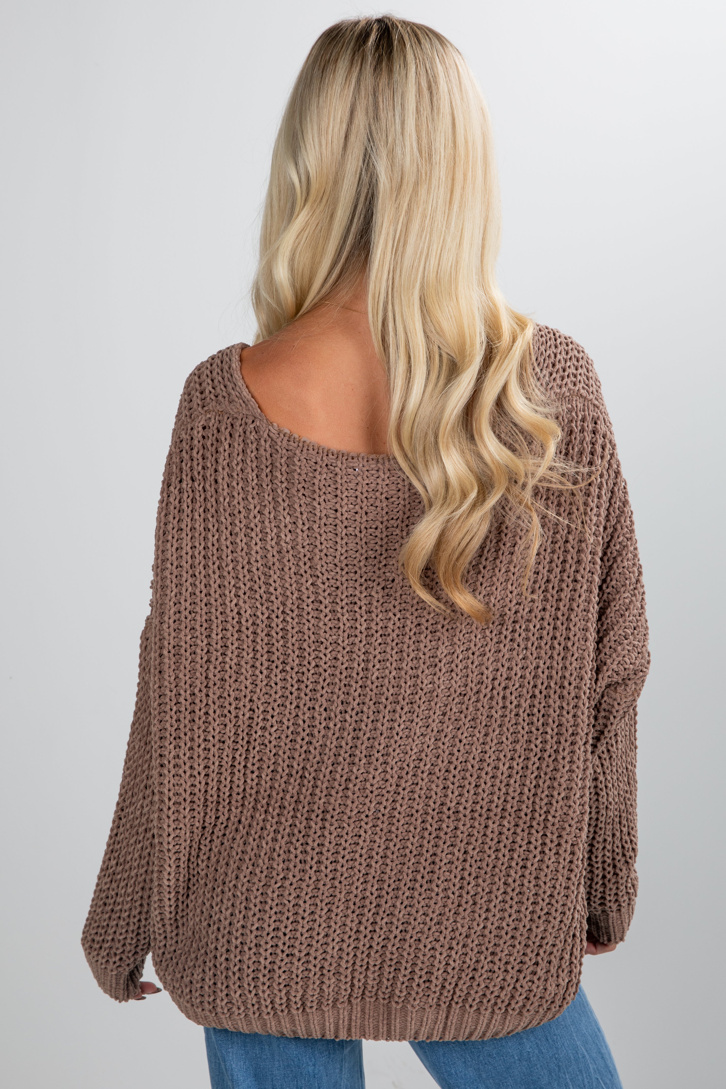 Person wearing a brown knitted sweater on a plain background