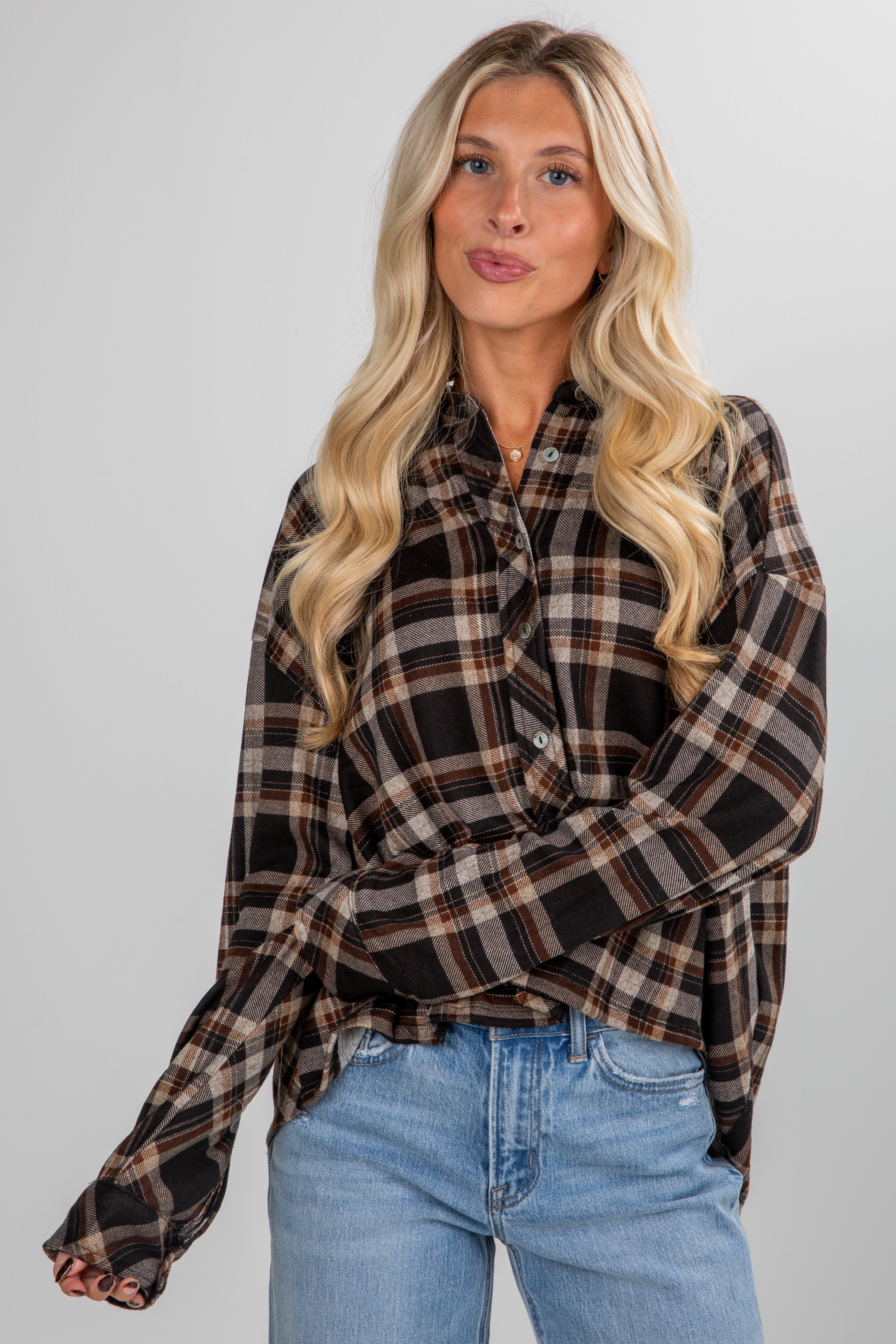 Woman wearing a plaid shirt and jeans against a plain background