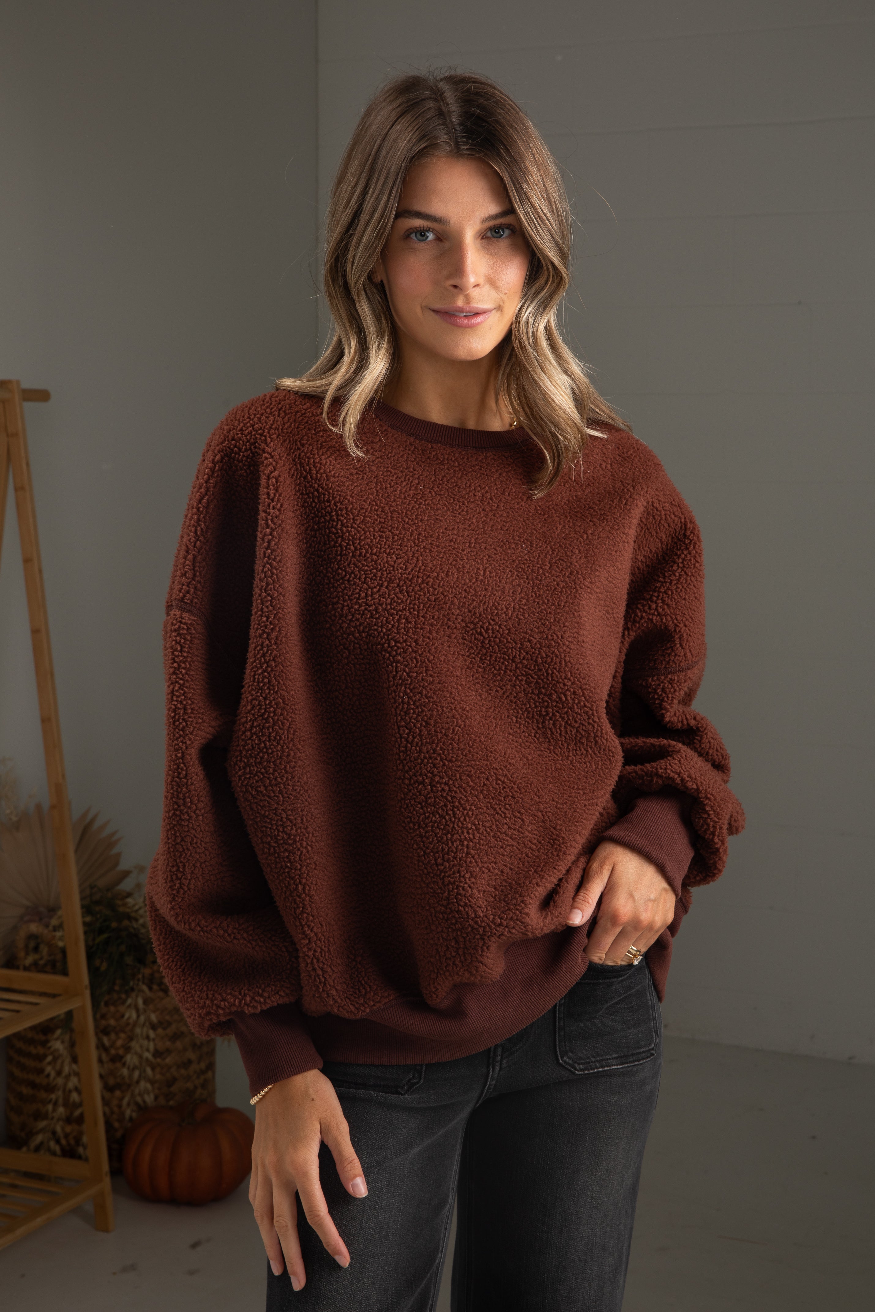 Woman wearing a brown sweater in a neutral setting