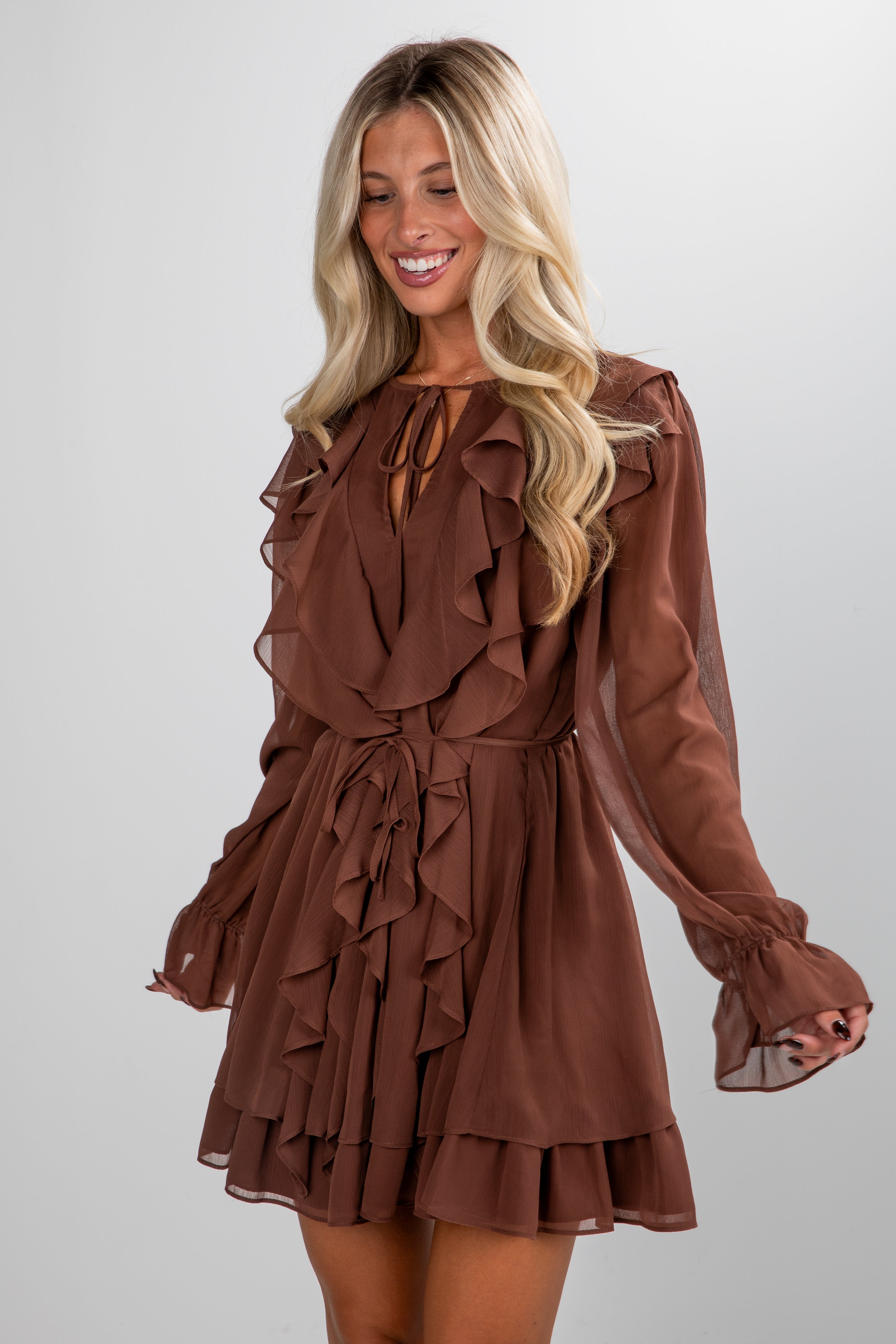 Woman wearing a brown ruffled dress on a plain background