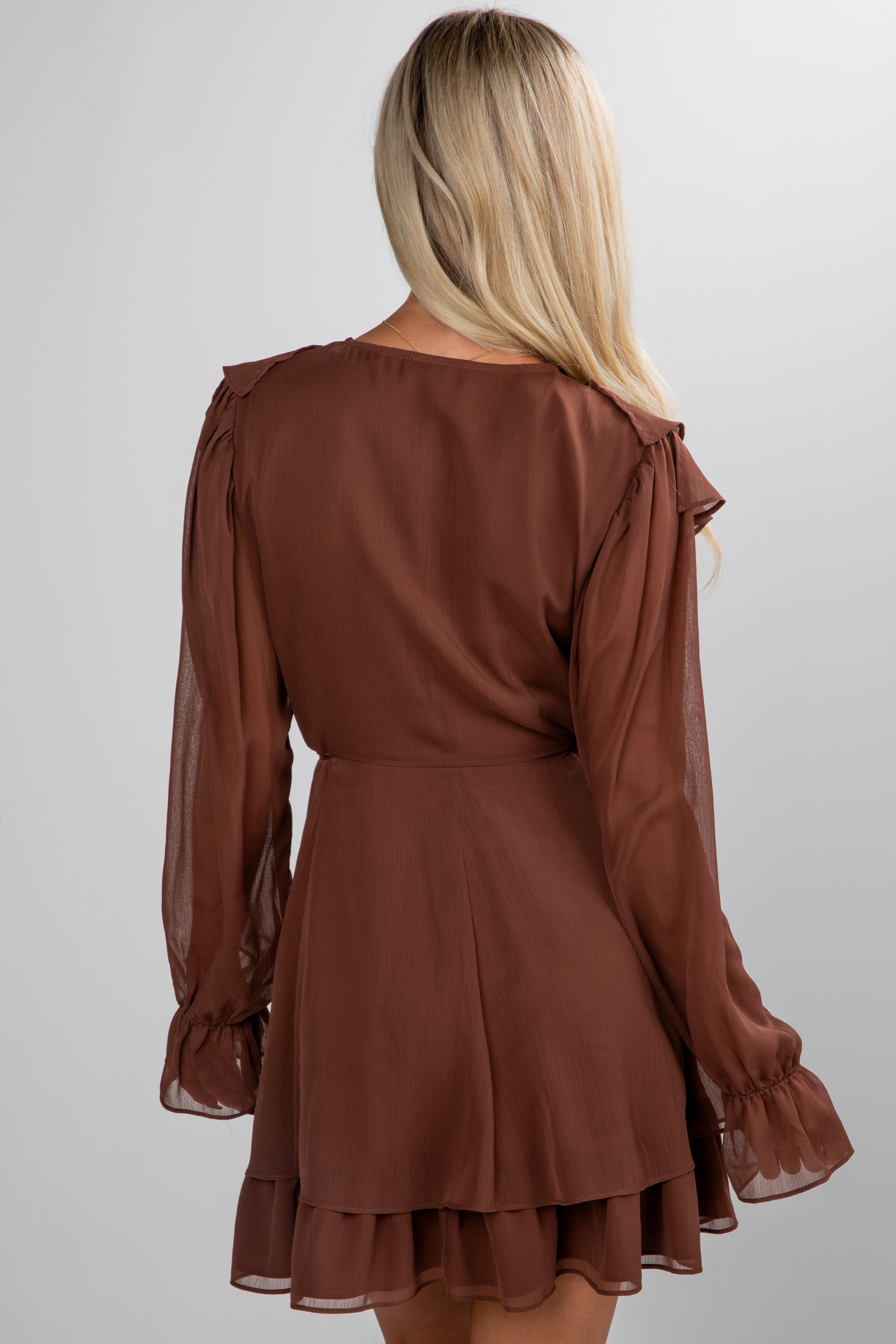 Brown dress with sheer sleeves worn by a person on a white background