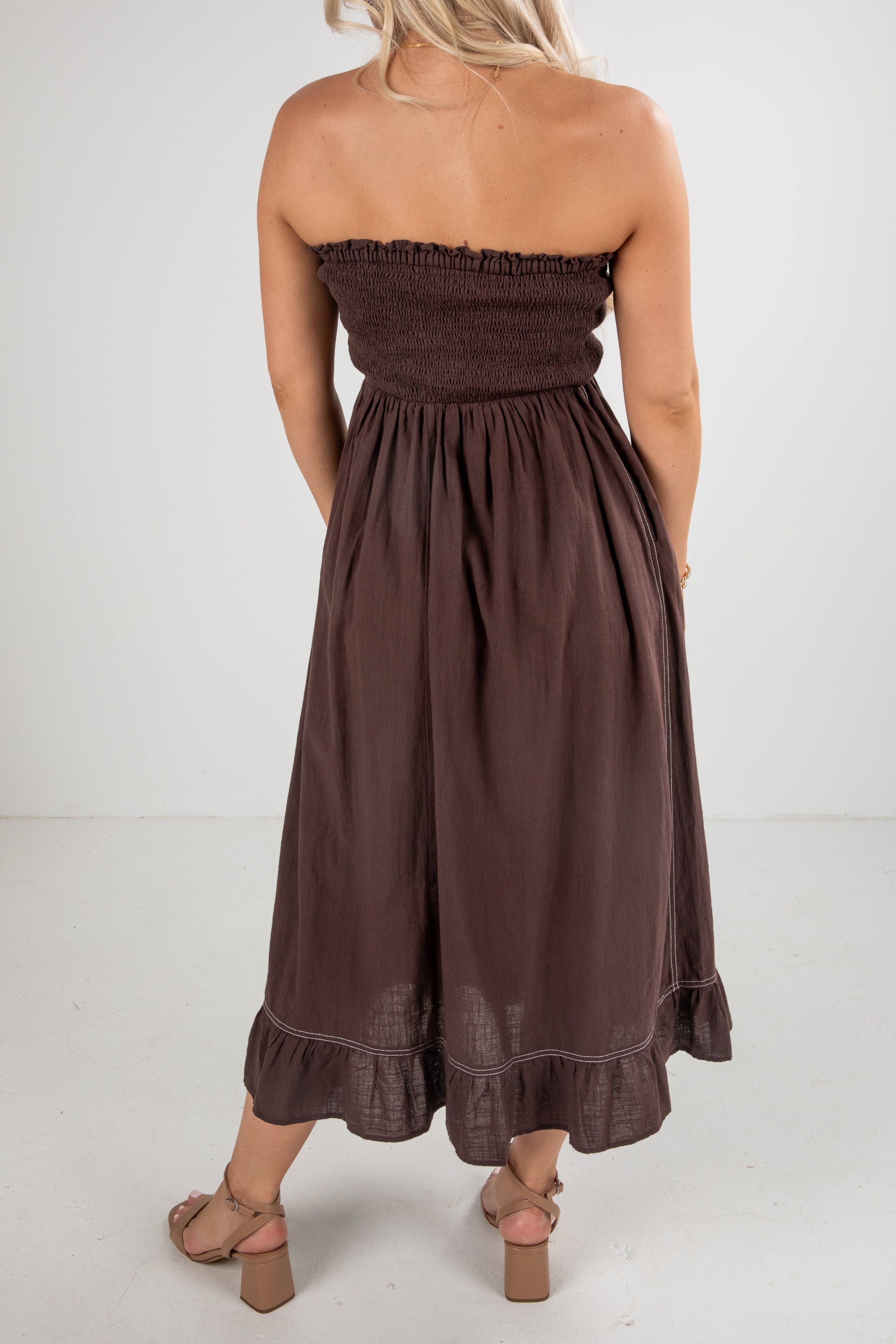 Brown strapless dress worn by a person on a white background
