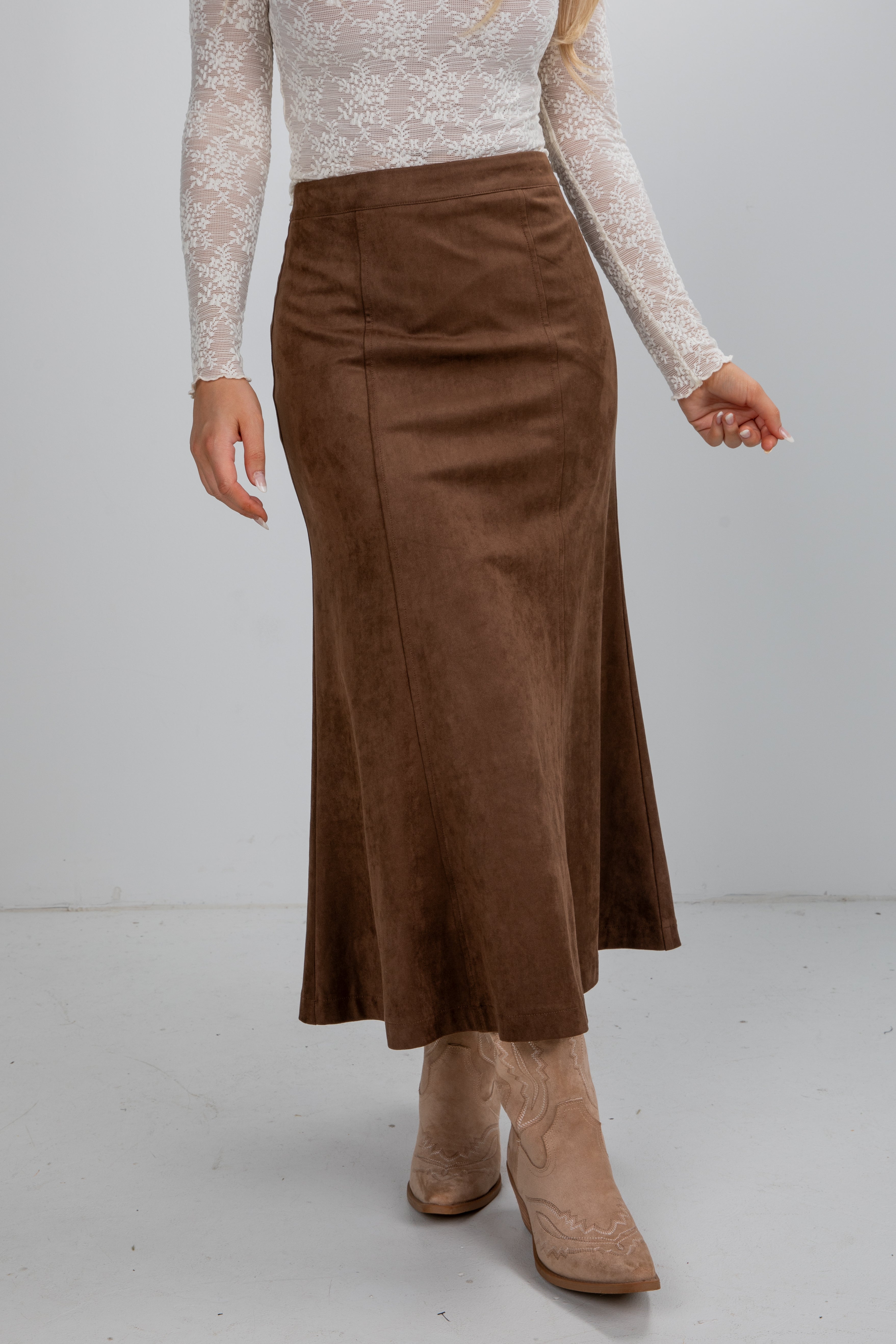 Person wearing a brown skirt and beige boots on a plain background
