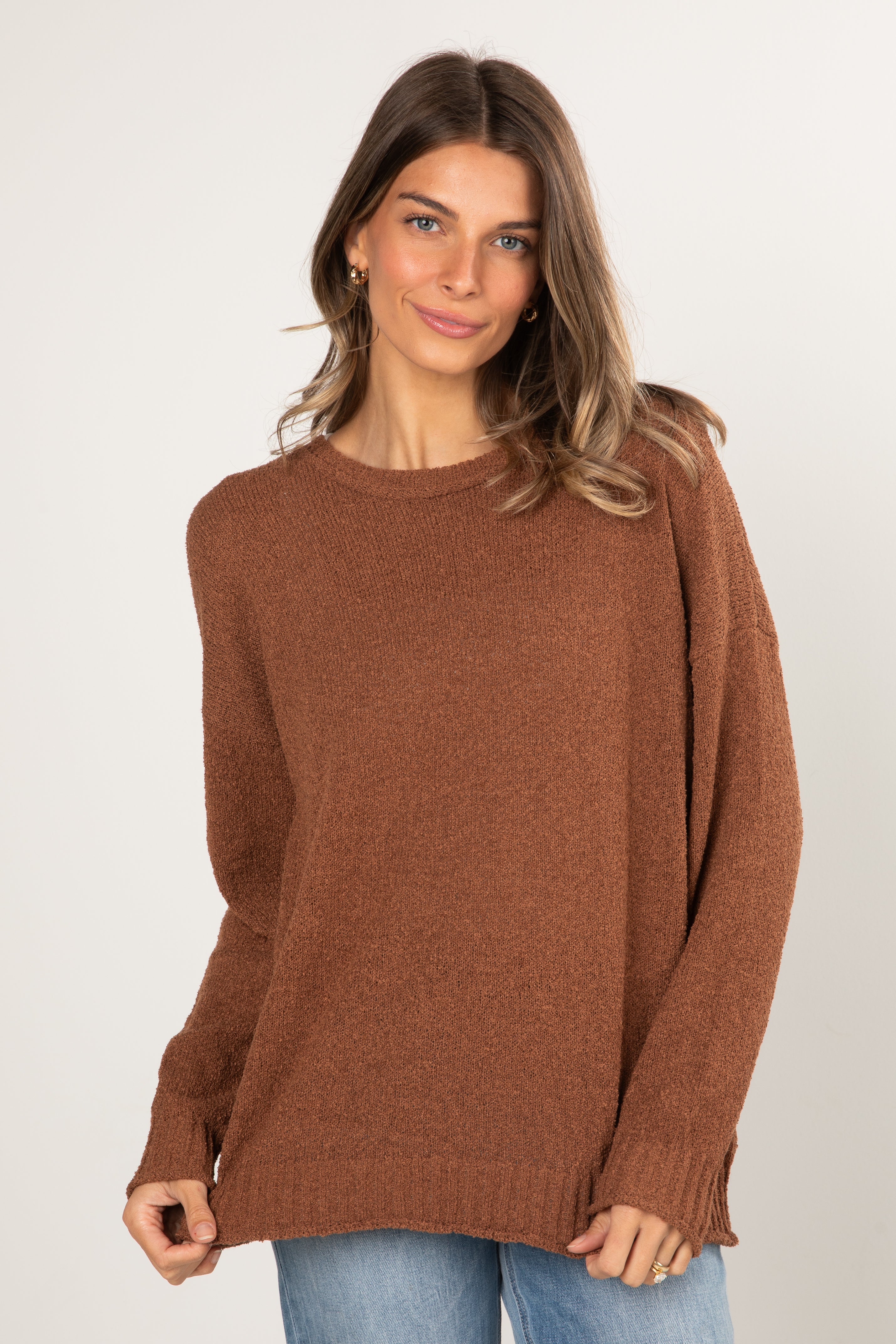 Woman wearing a brown sweater against a white background