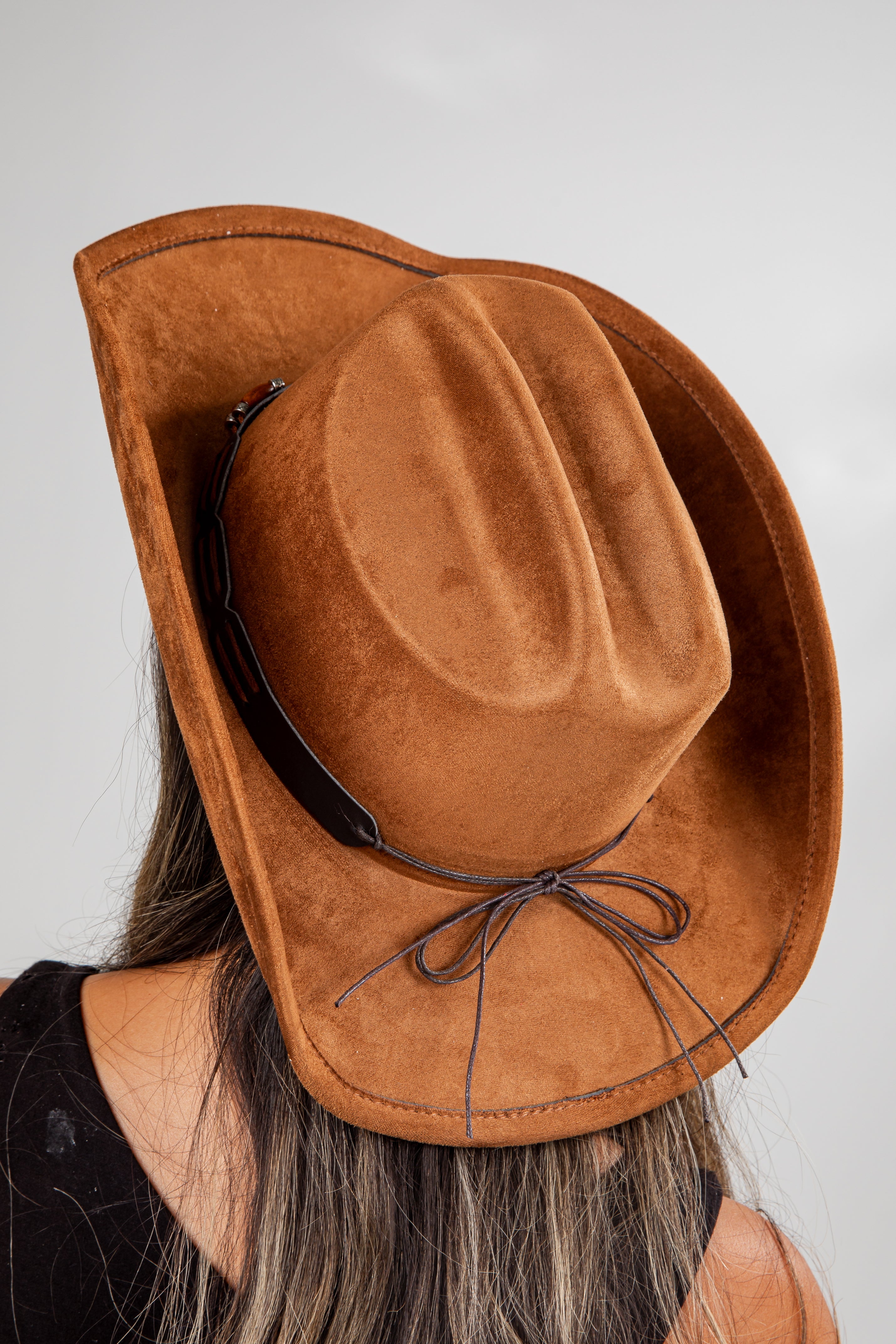 Brown cowboy hat with a ribbon on a plain background