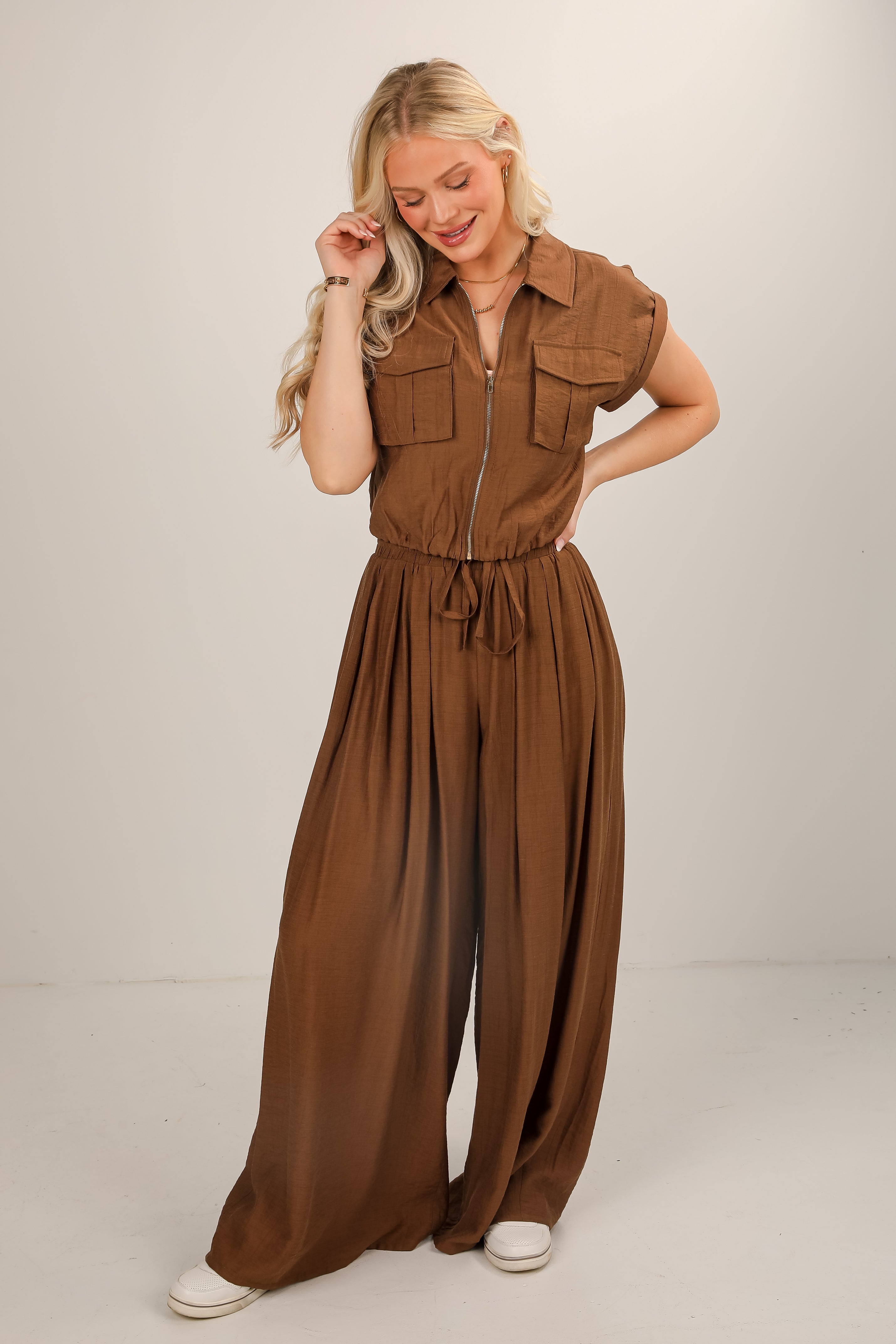 Woman wearing a brown jumpsuit on a plain background