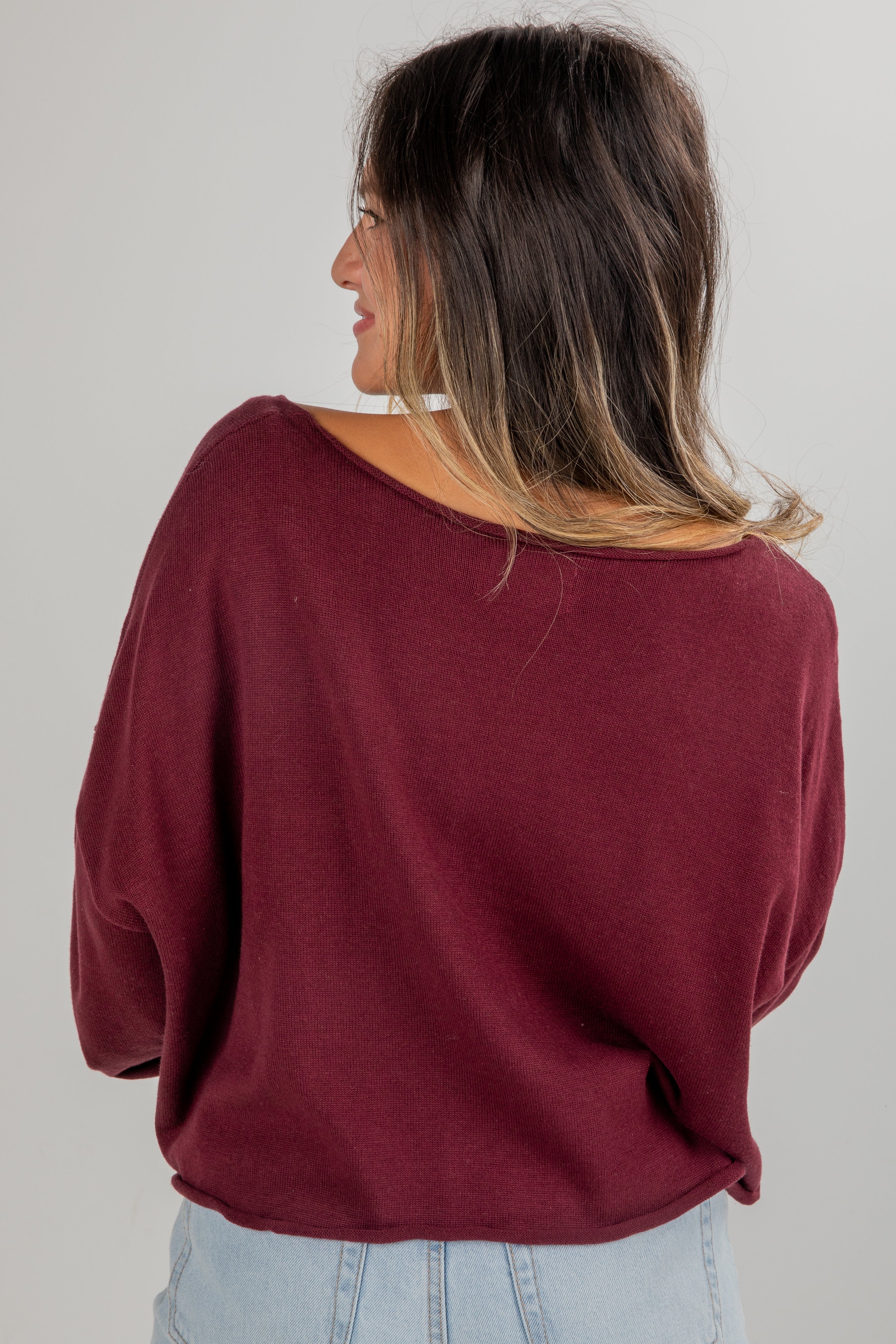 Woman wearing a burgundy sweater against a plain background