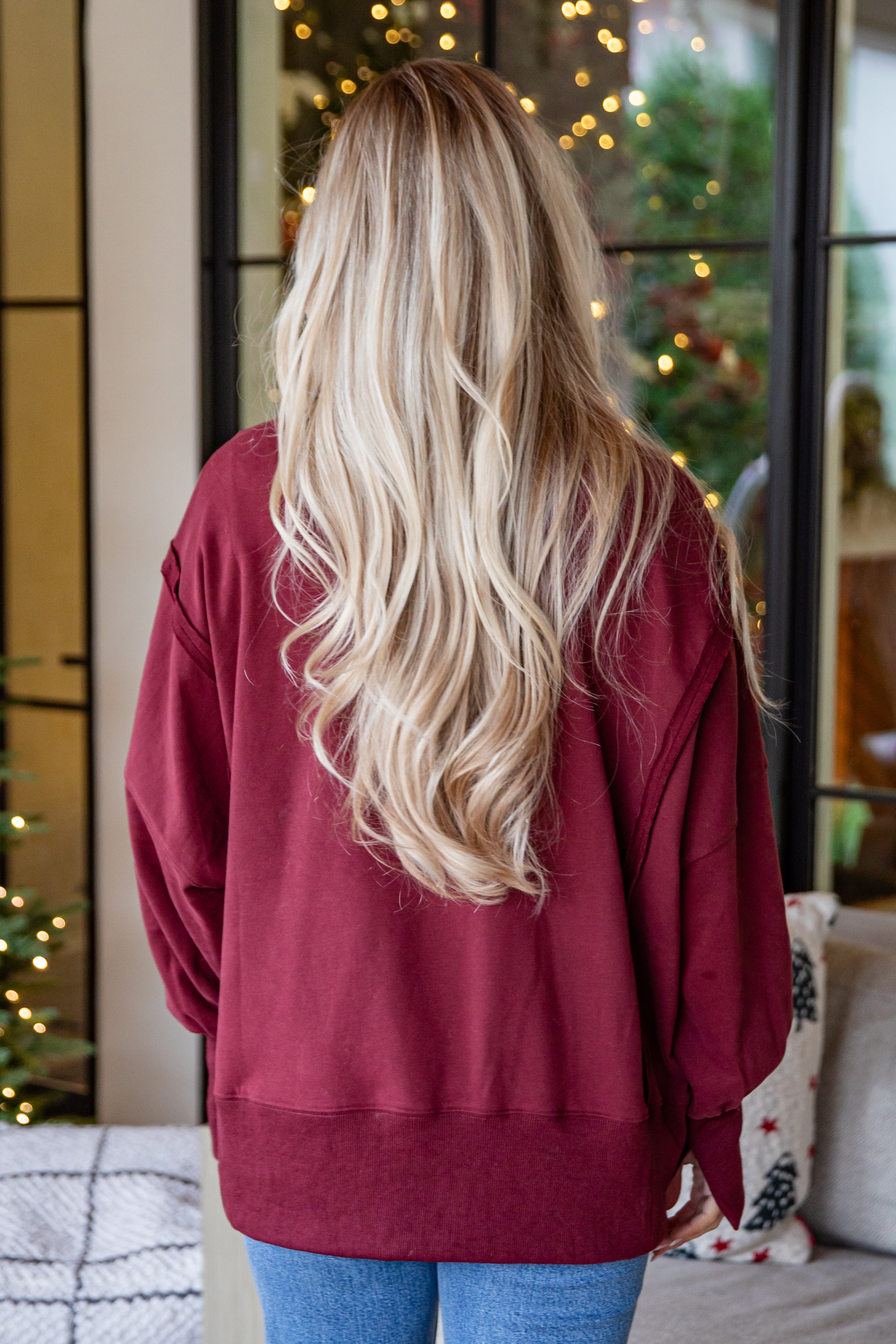 Person wearing a red sweater with a blurred background of a decorated room.