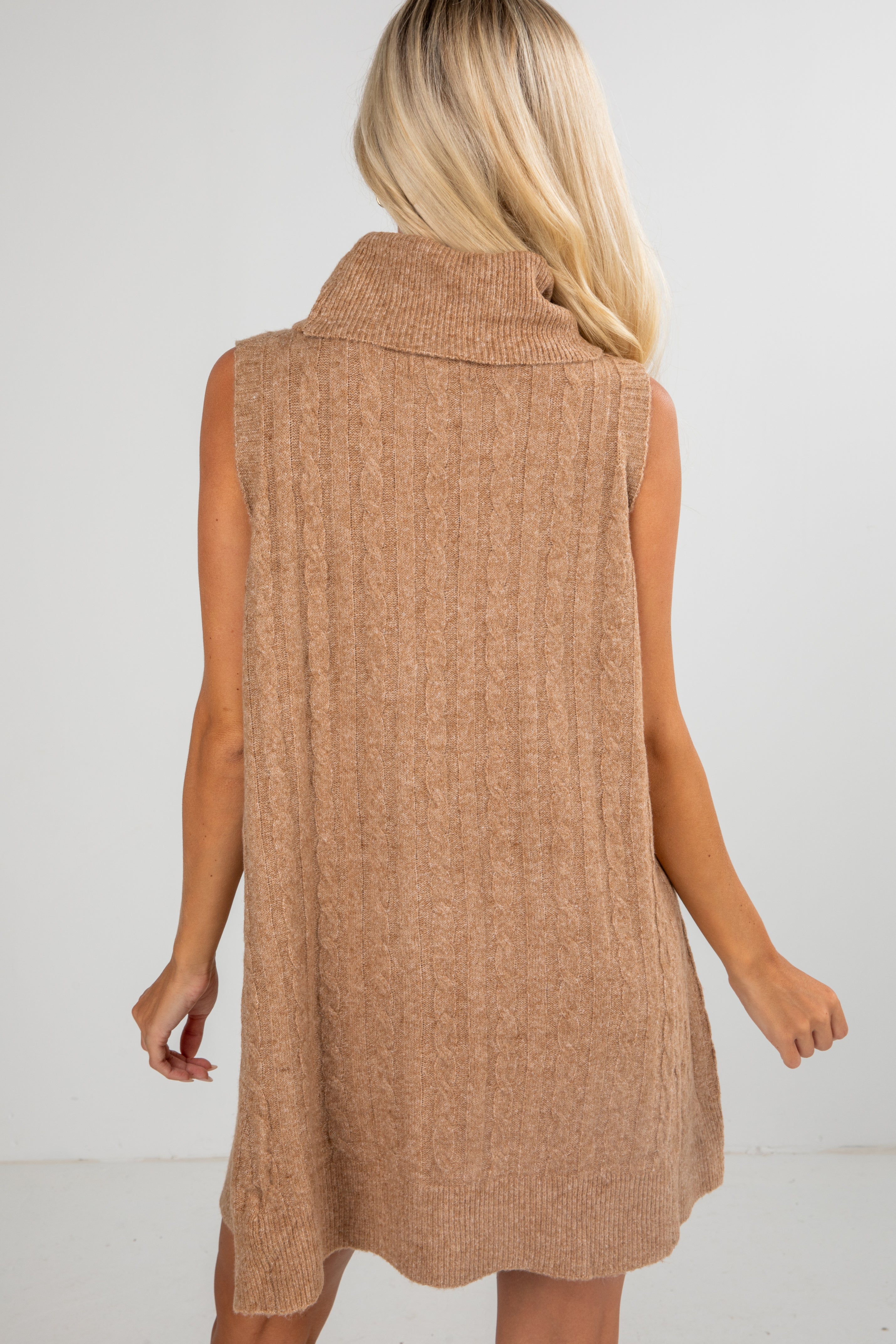 Woman wearing a brown sleeveless dress against a white background