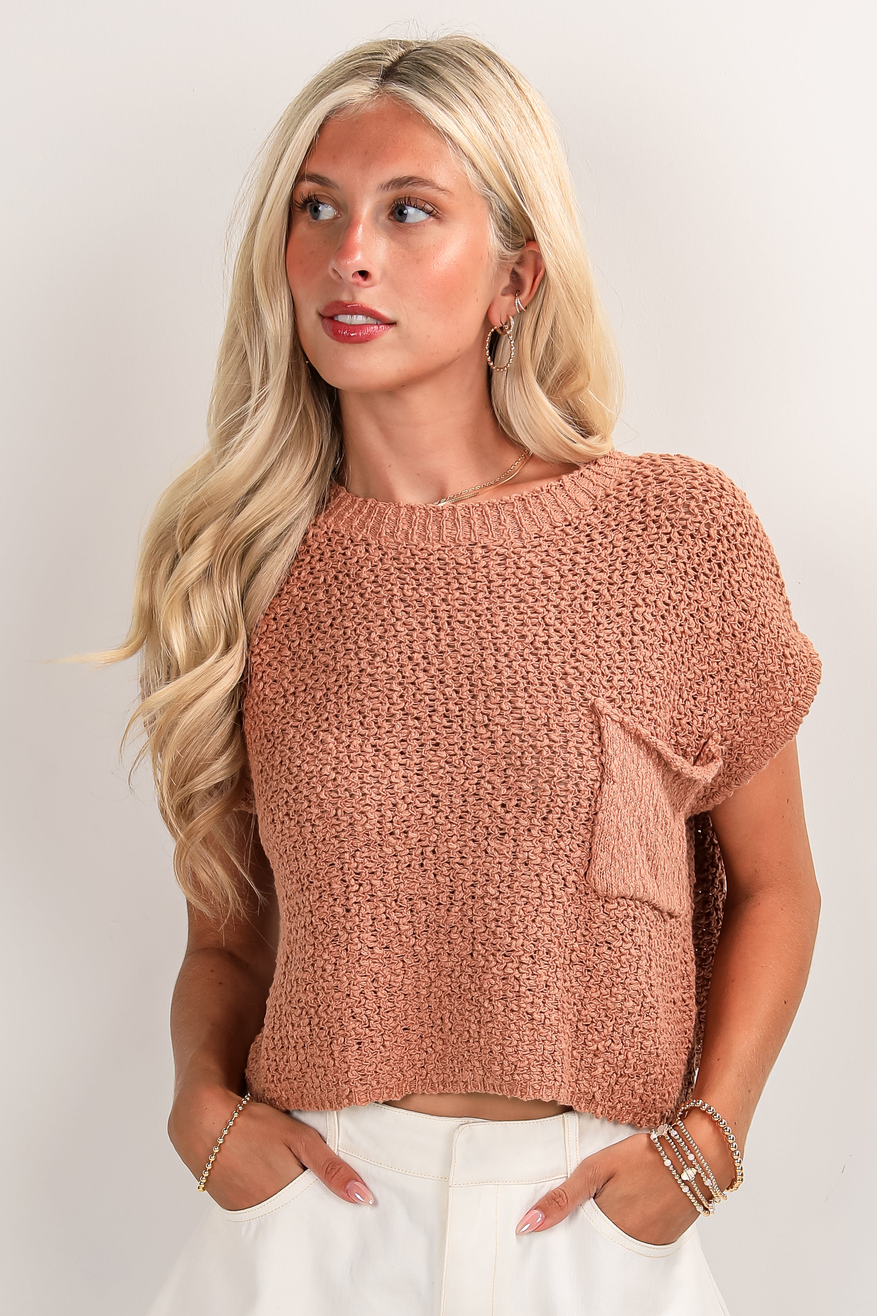 Woman wearing a brown knitted top against a plain background