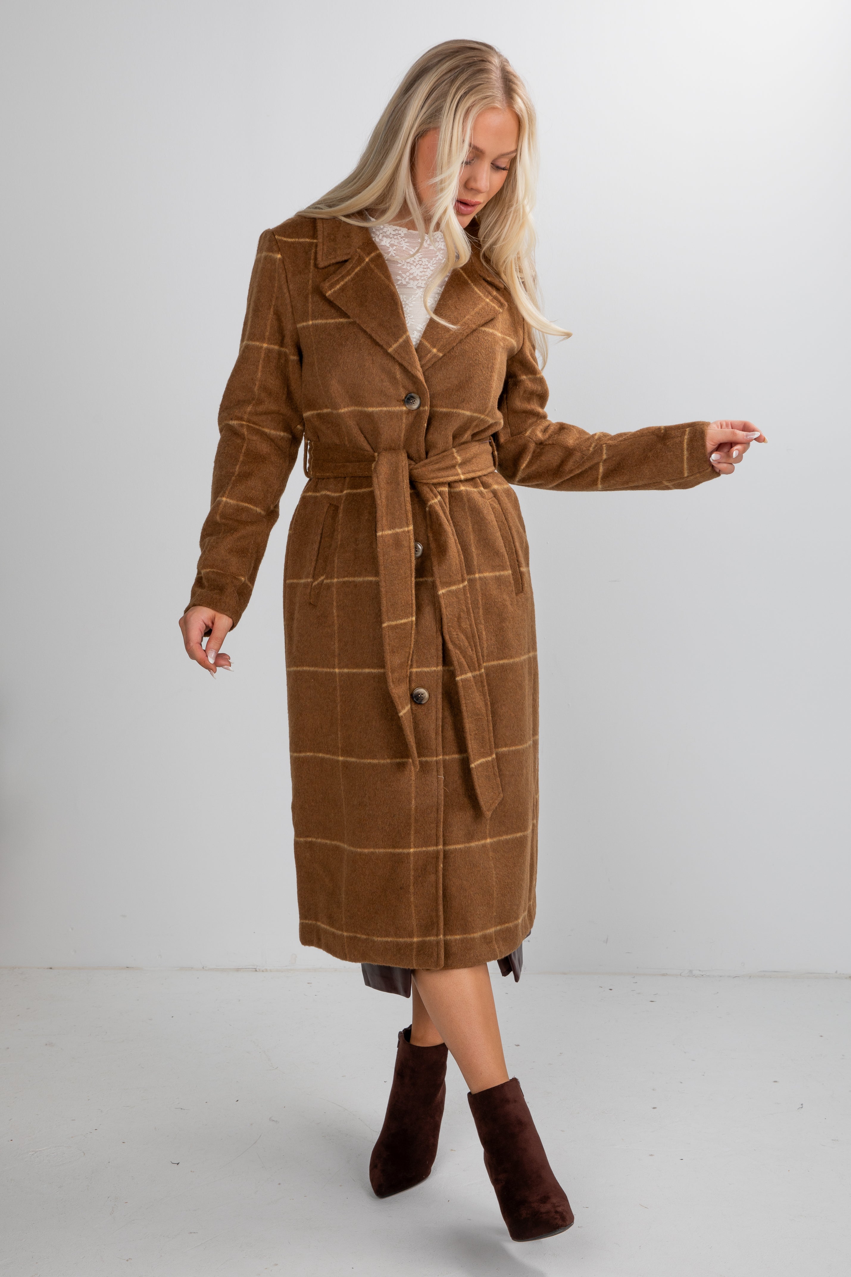 Woman wearing a brown plaid coat on a white background