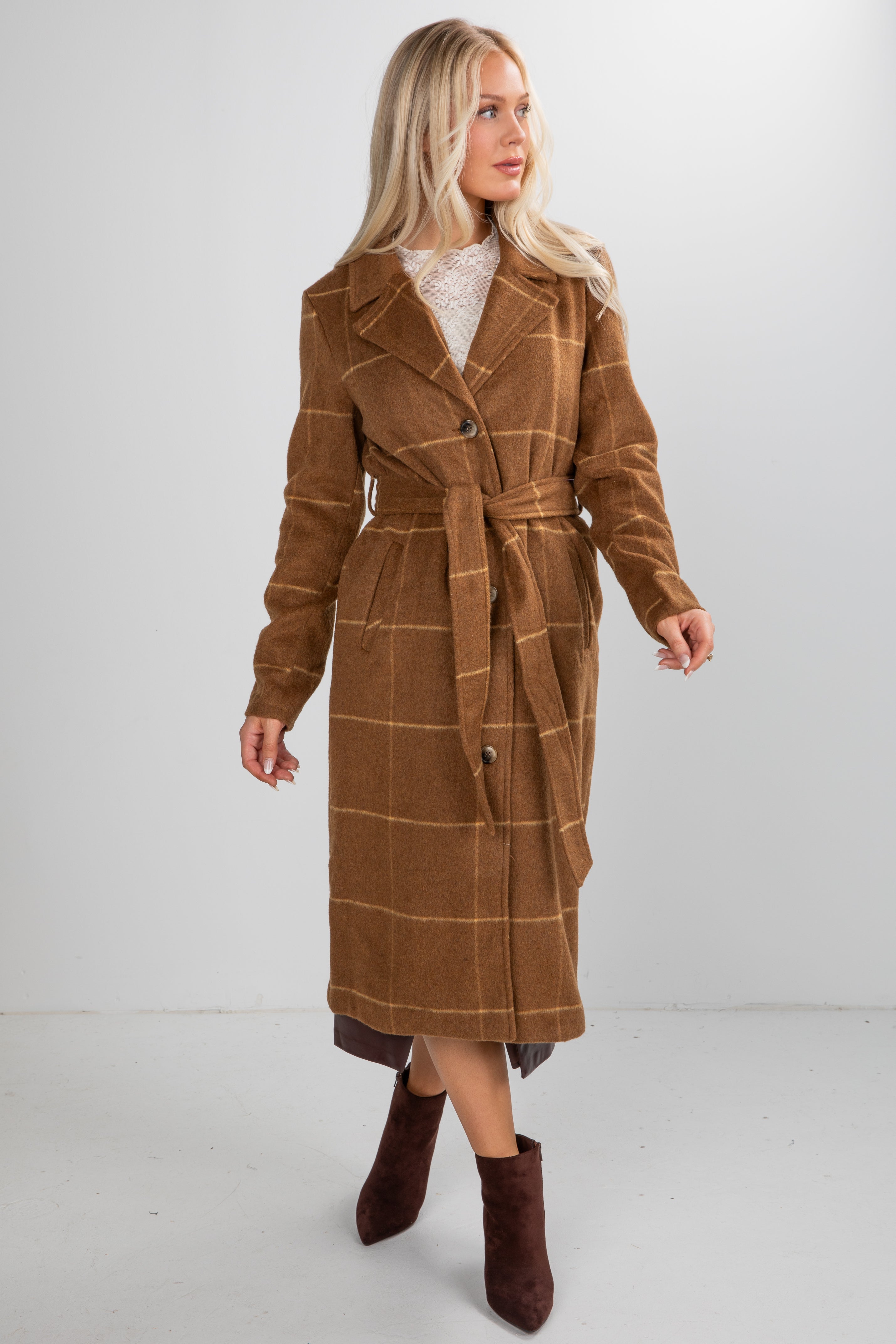Woman wearing a brown plaid coat on a white background