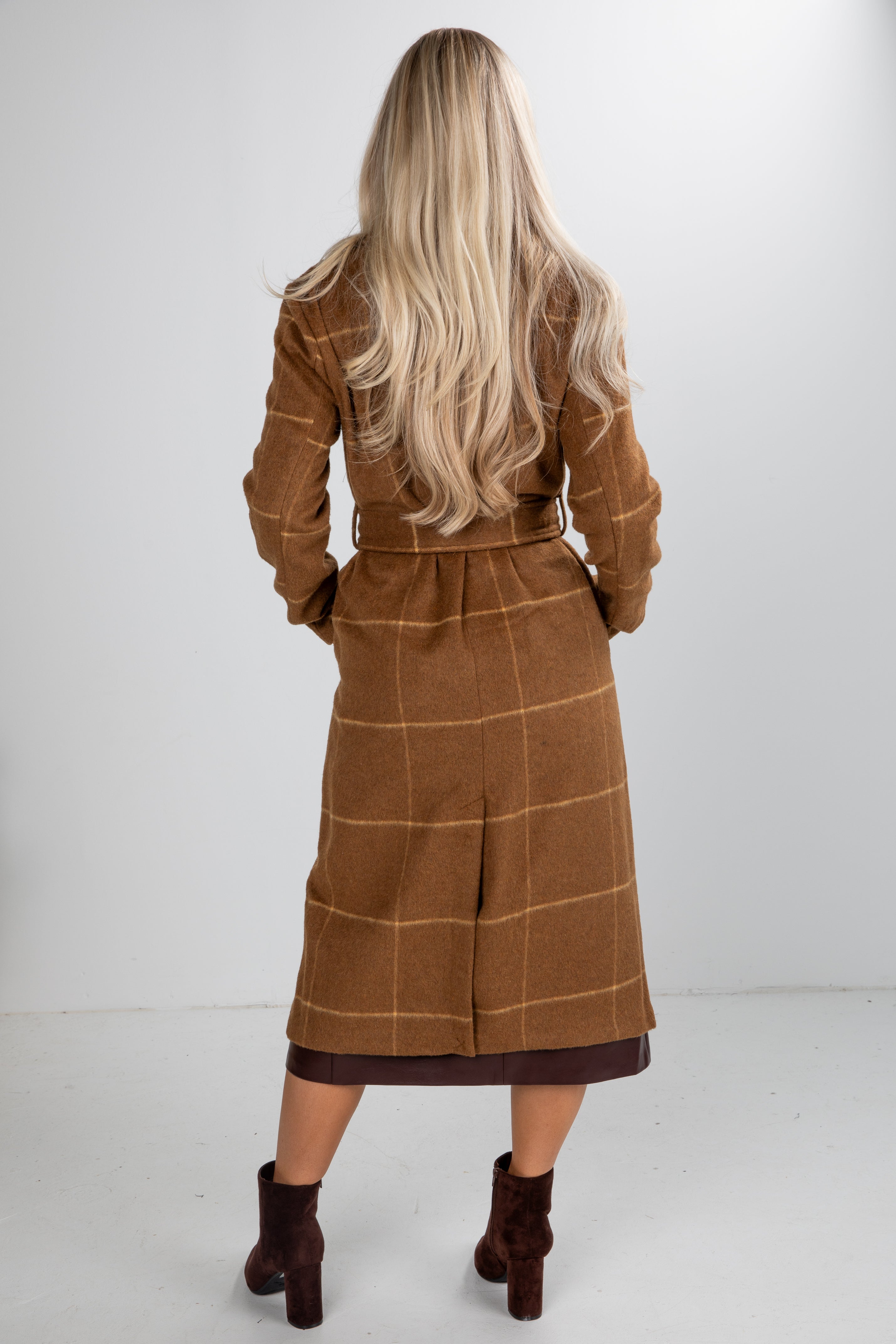 Woman wearing a brown checkered coat against a white background