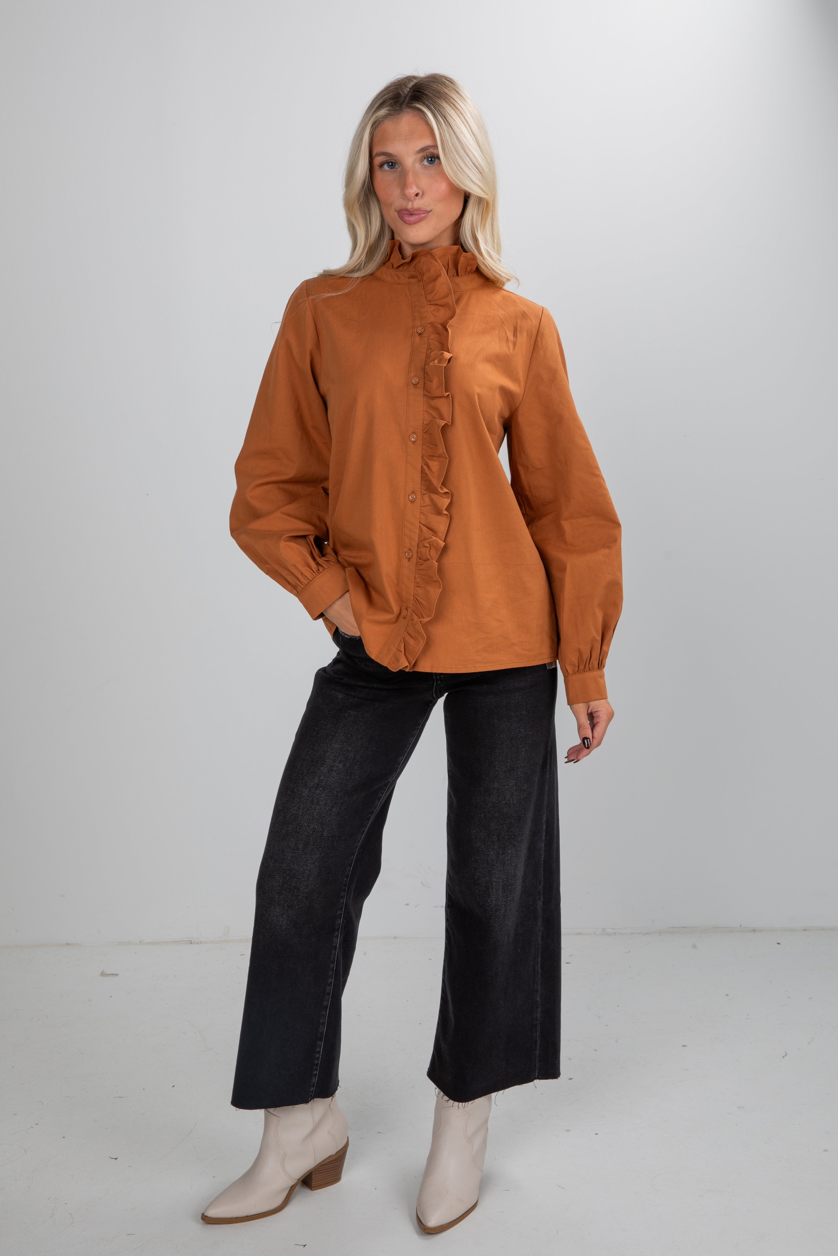 Woman wearing a brown blouse and black pants on a white background