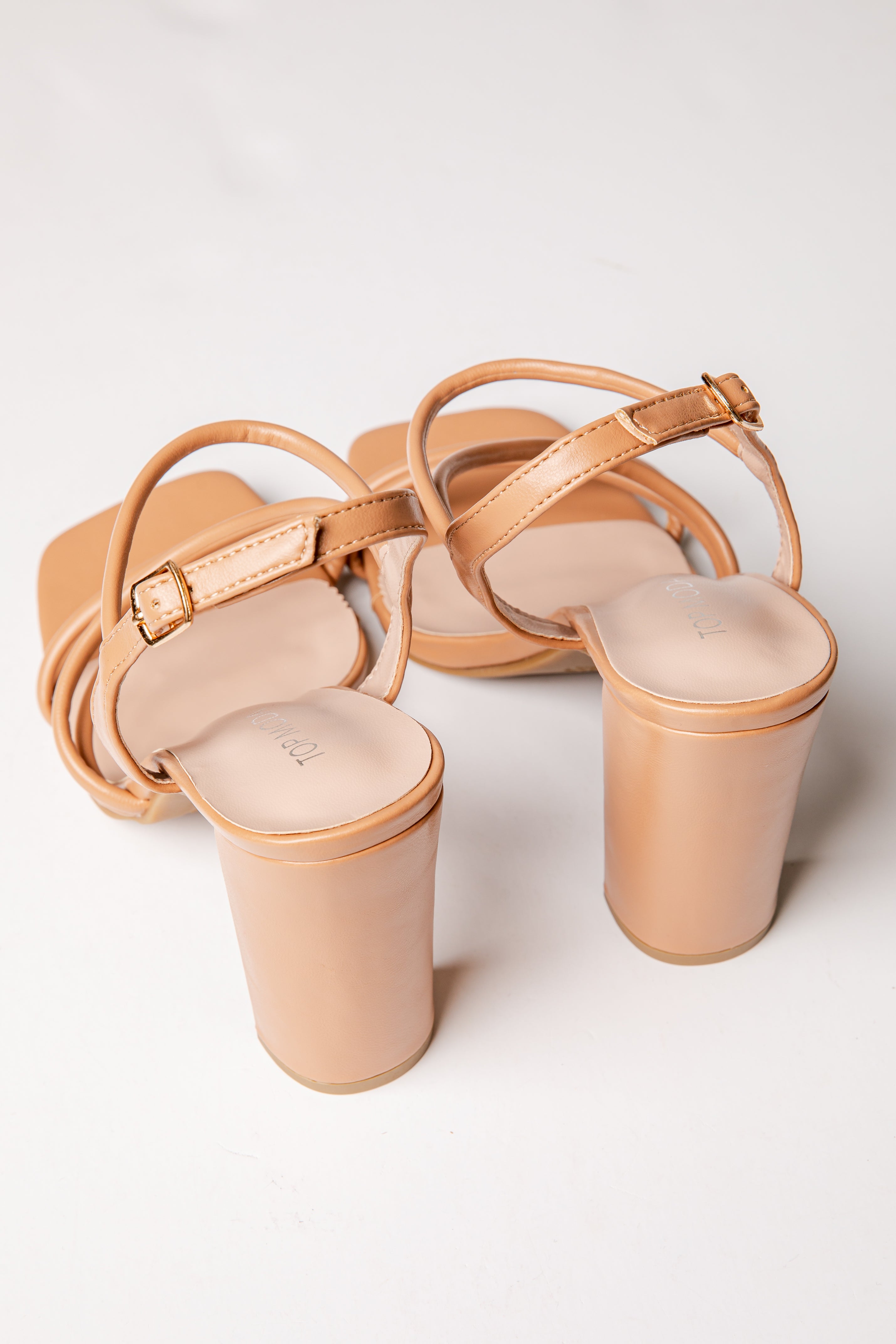 Pair of beige high-heeled sandals on a white background