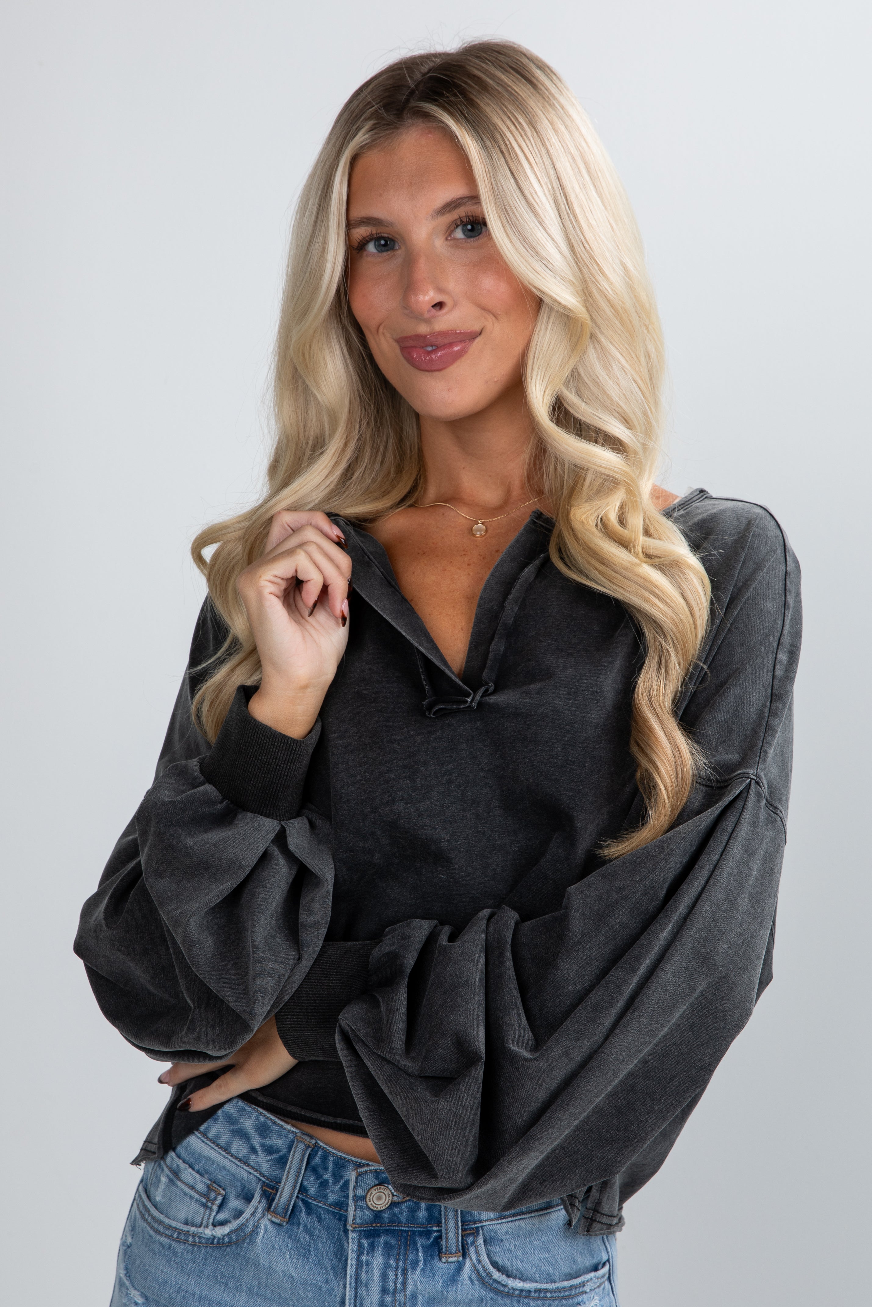 Woman wearing a black oversized sweater and blue jeans on a plain background