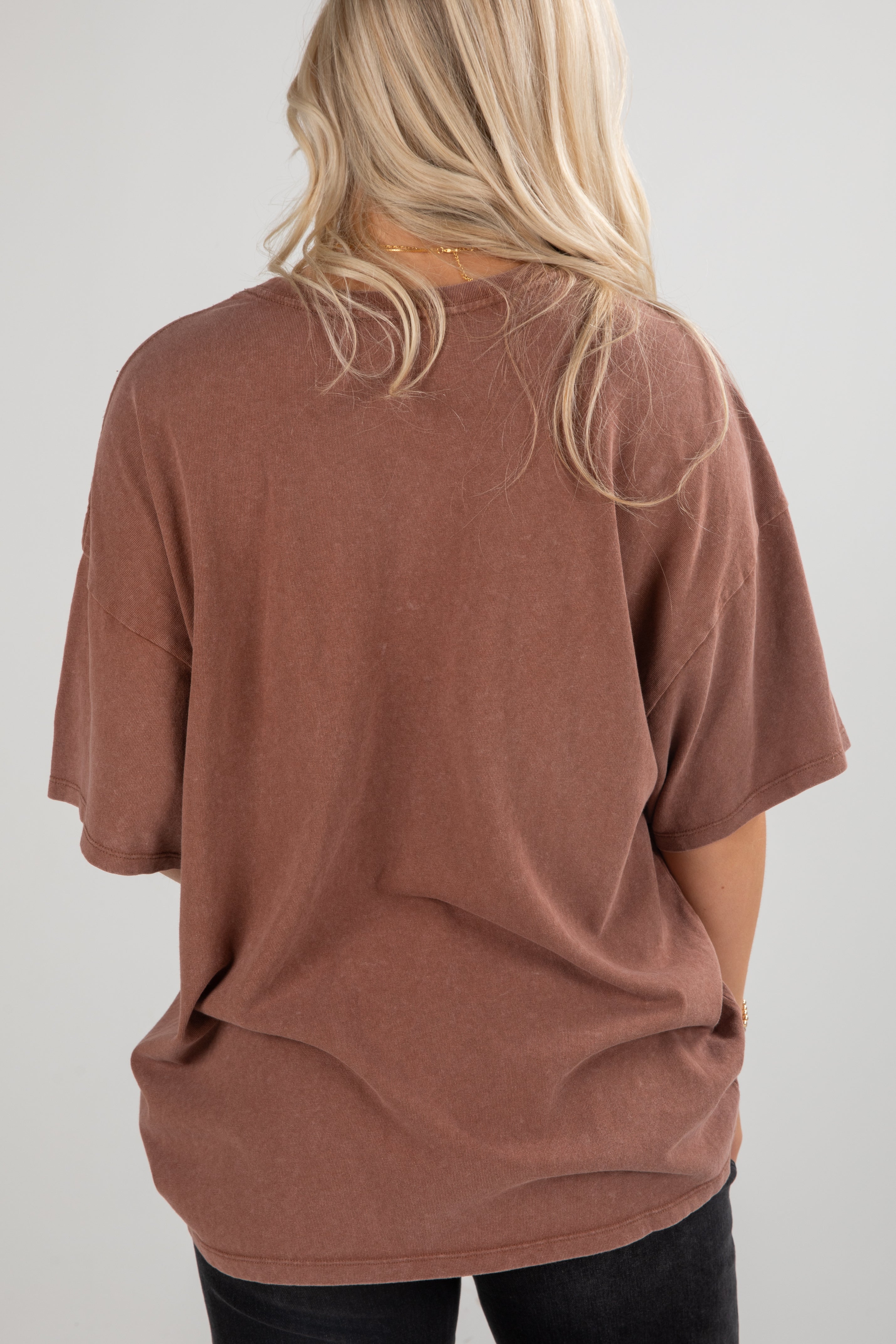 Person wearing a brown oversized t-shirt on a plain background