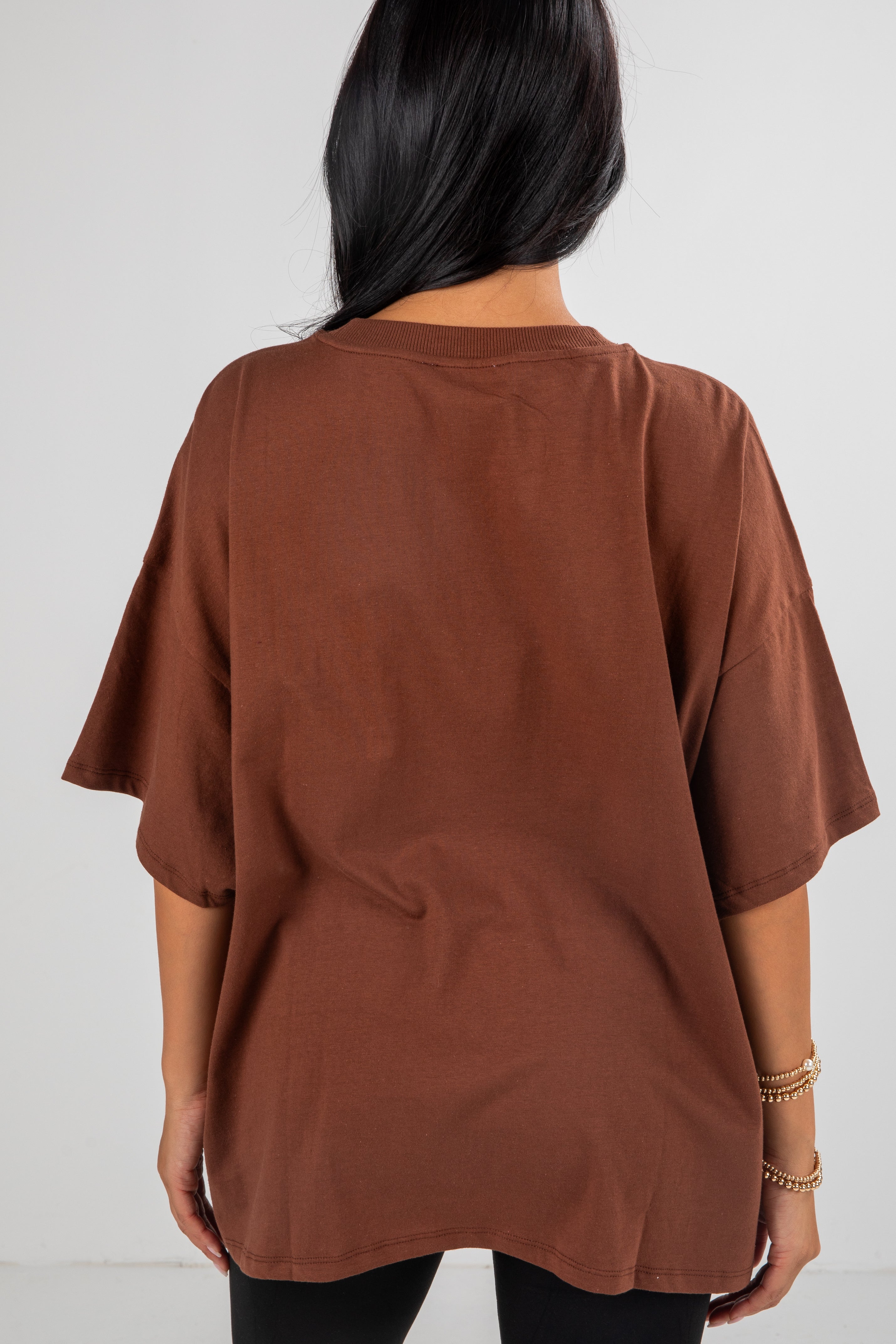Brown oversized t-shirt worn by a person on a white background
