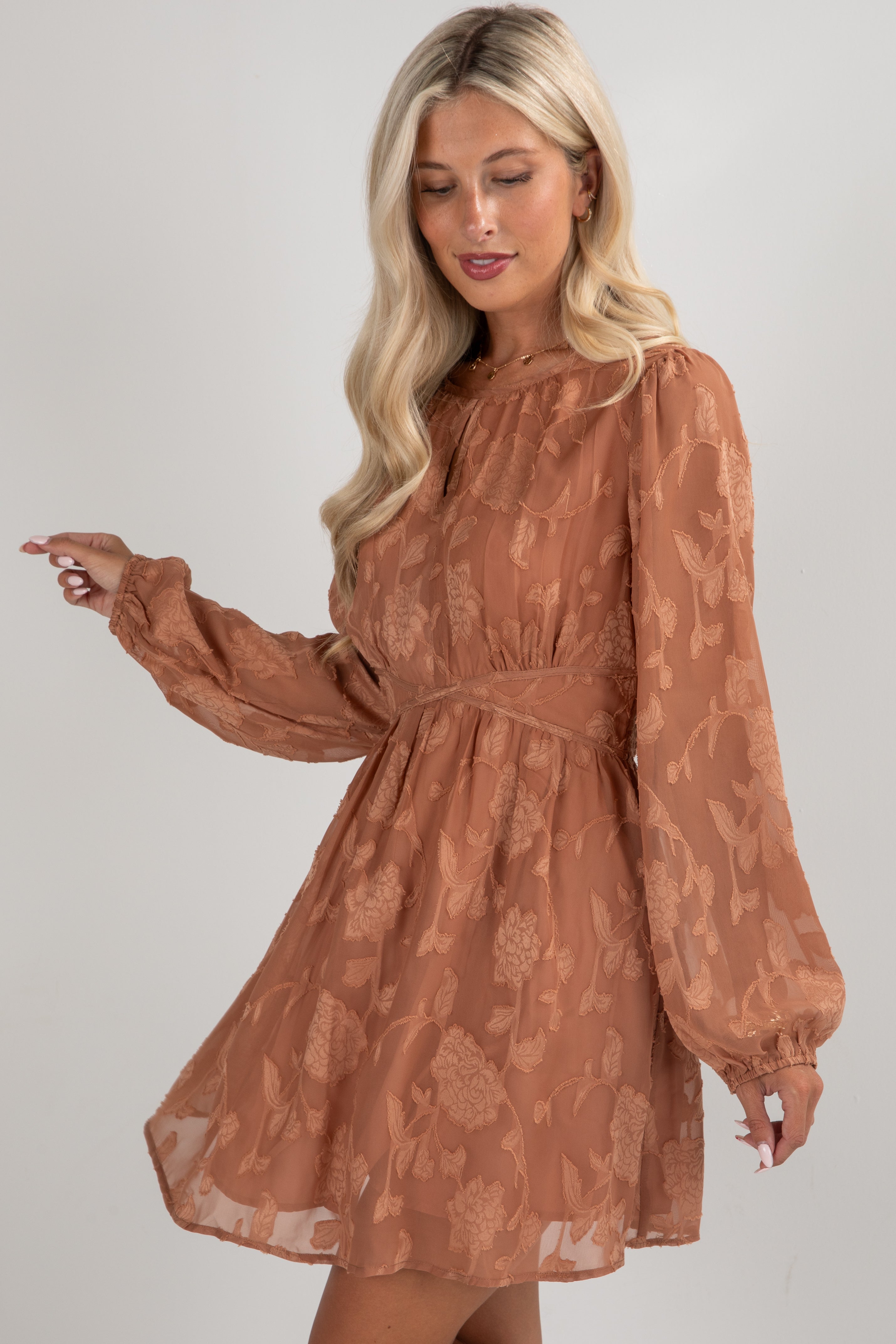 Woman wearing a brown floral dress against a plain background