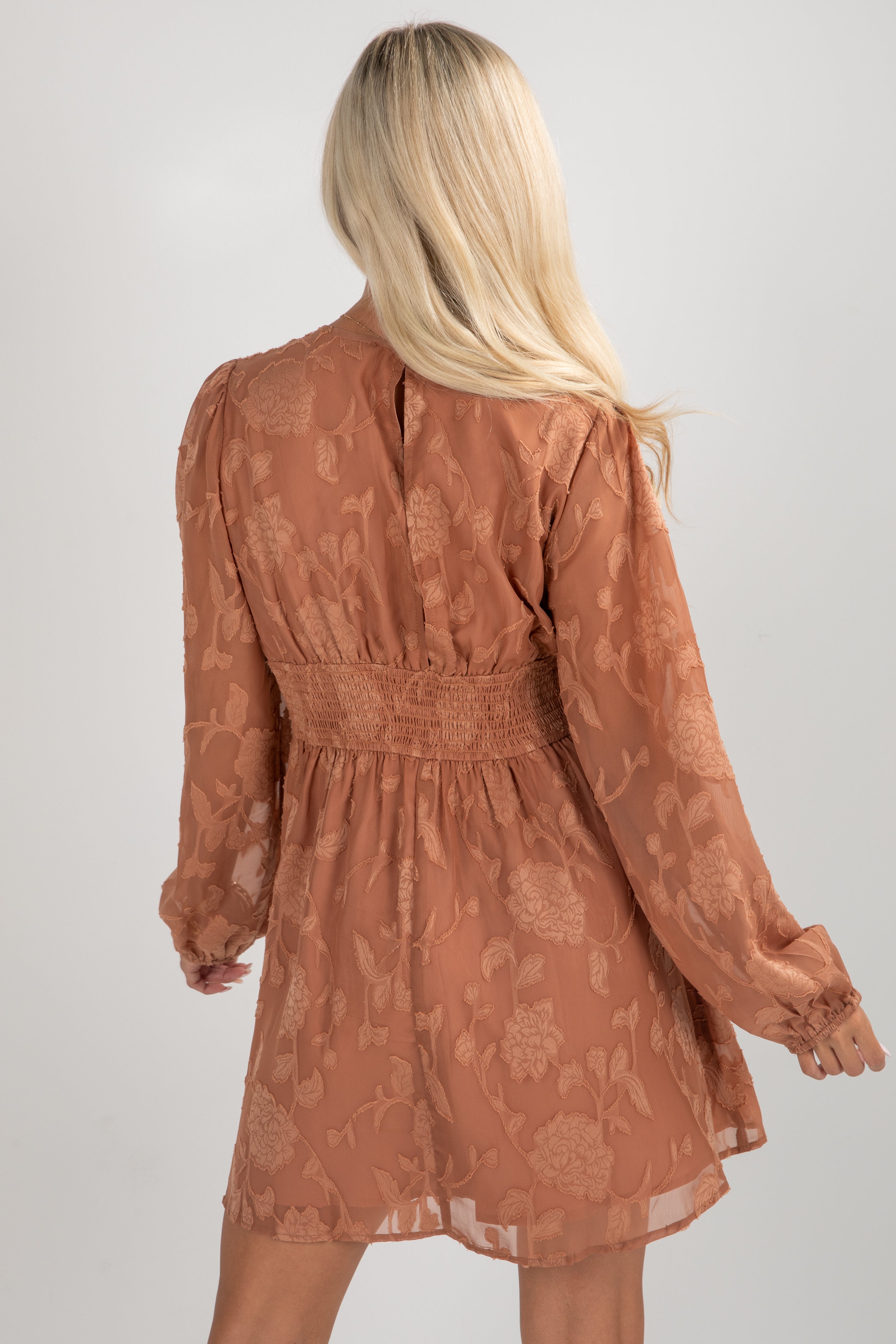 Woman wearing a brown floral dress against a plain background