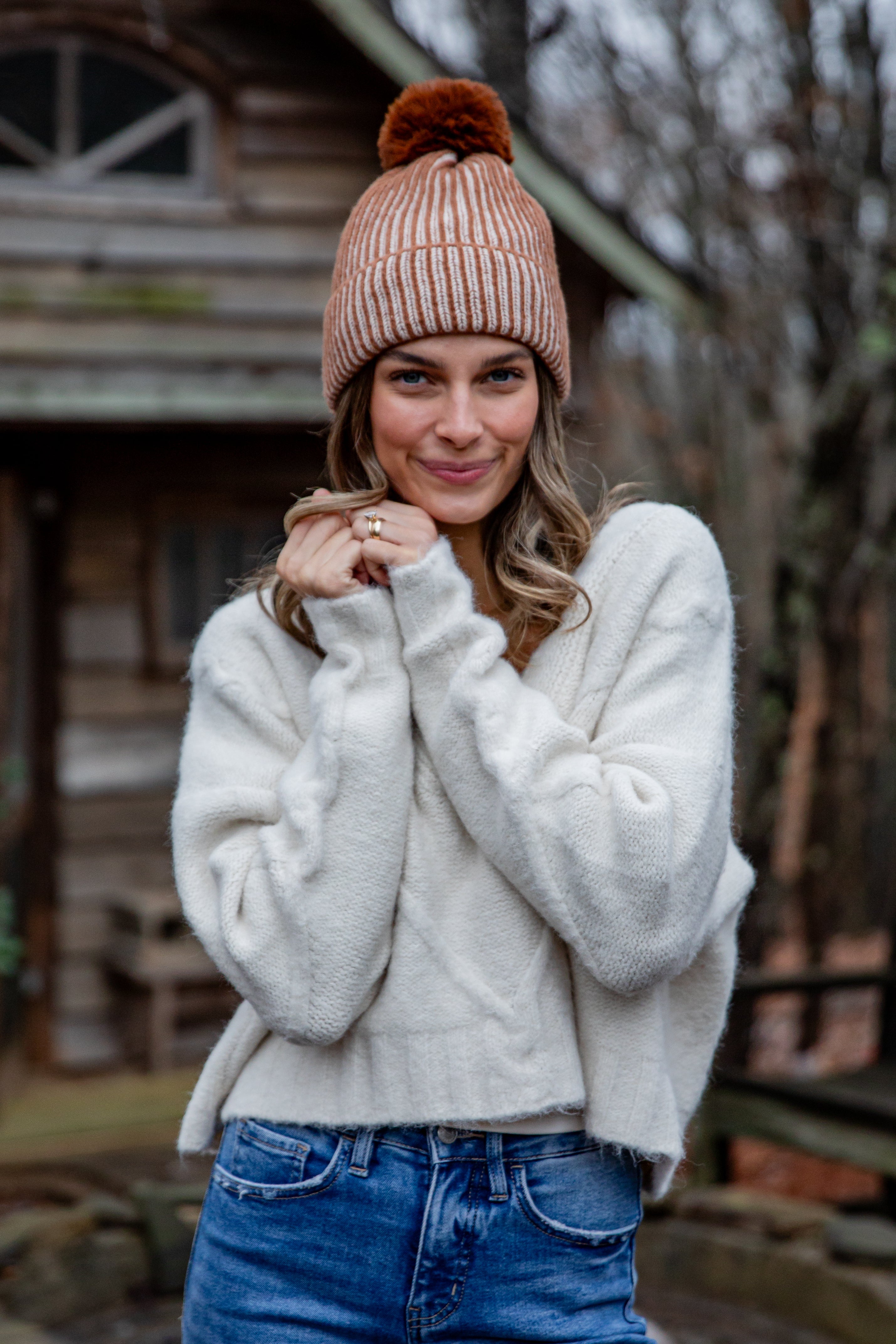 Woman wearing a beige knit hat and white sweater outdoors