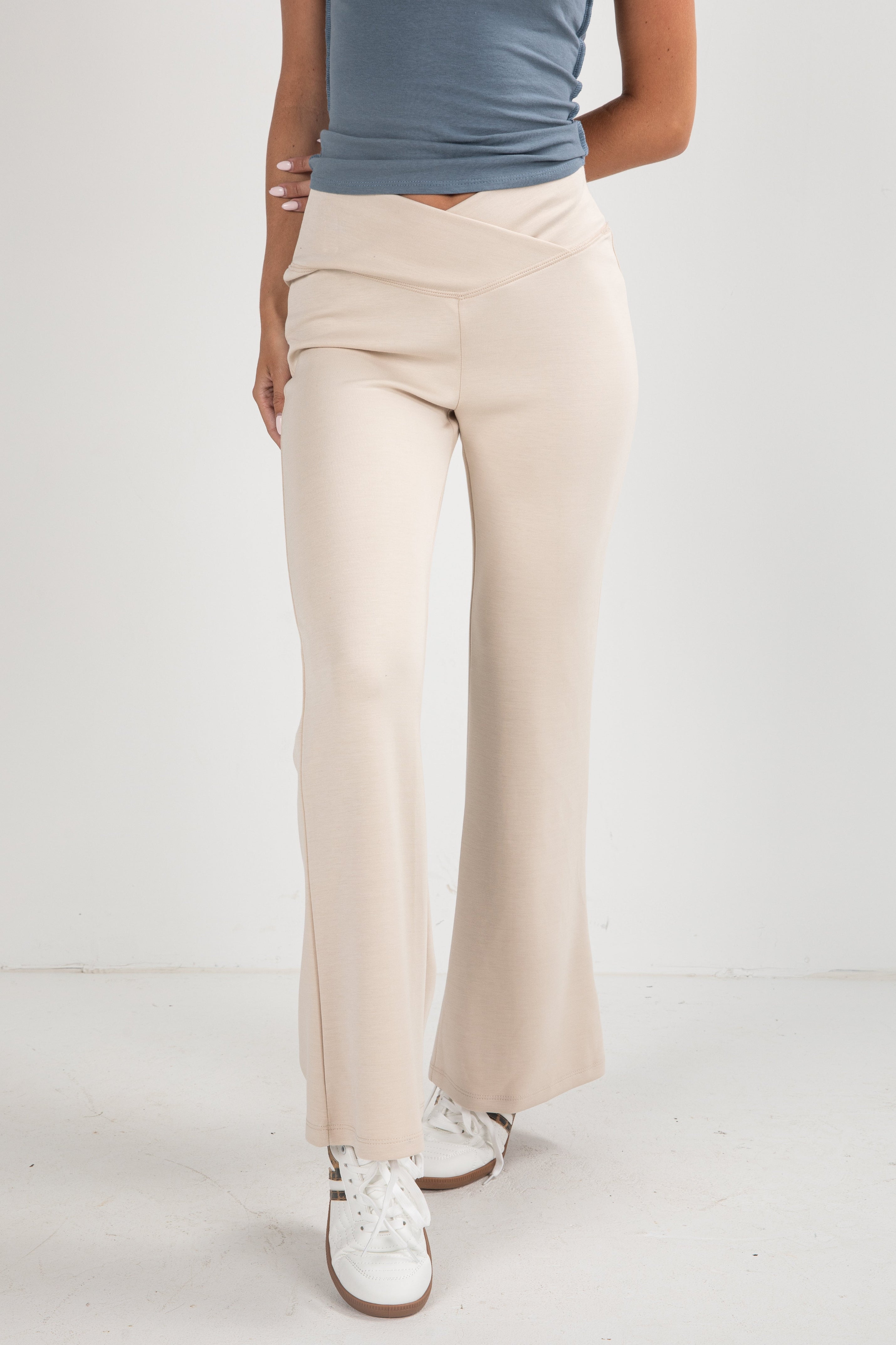 Person wearing beige wide-leg pants and a blue top on a white background