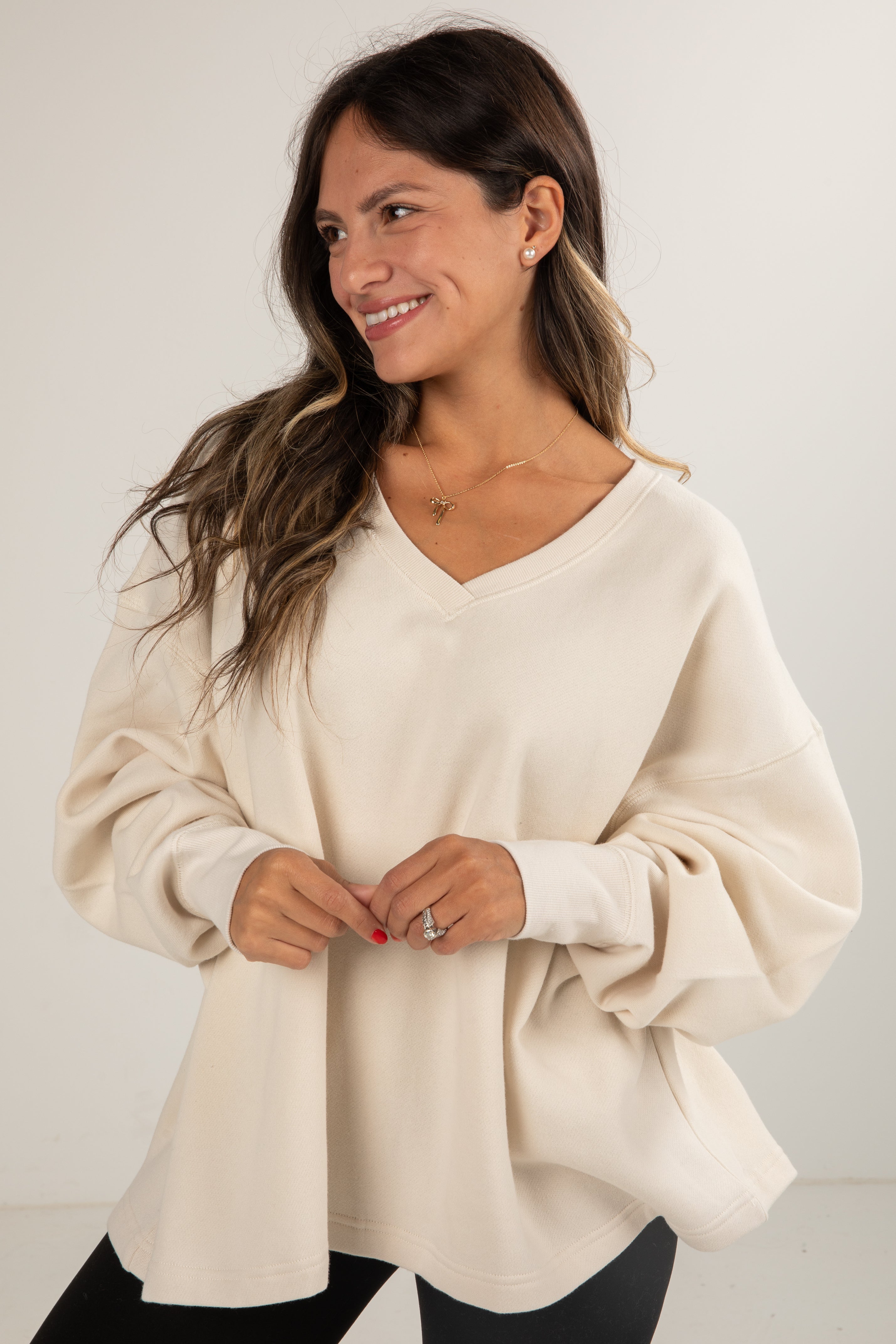 Woman wearing a beige sweater against a plain background