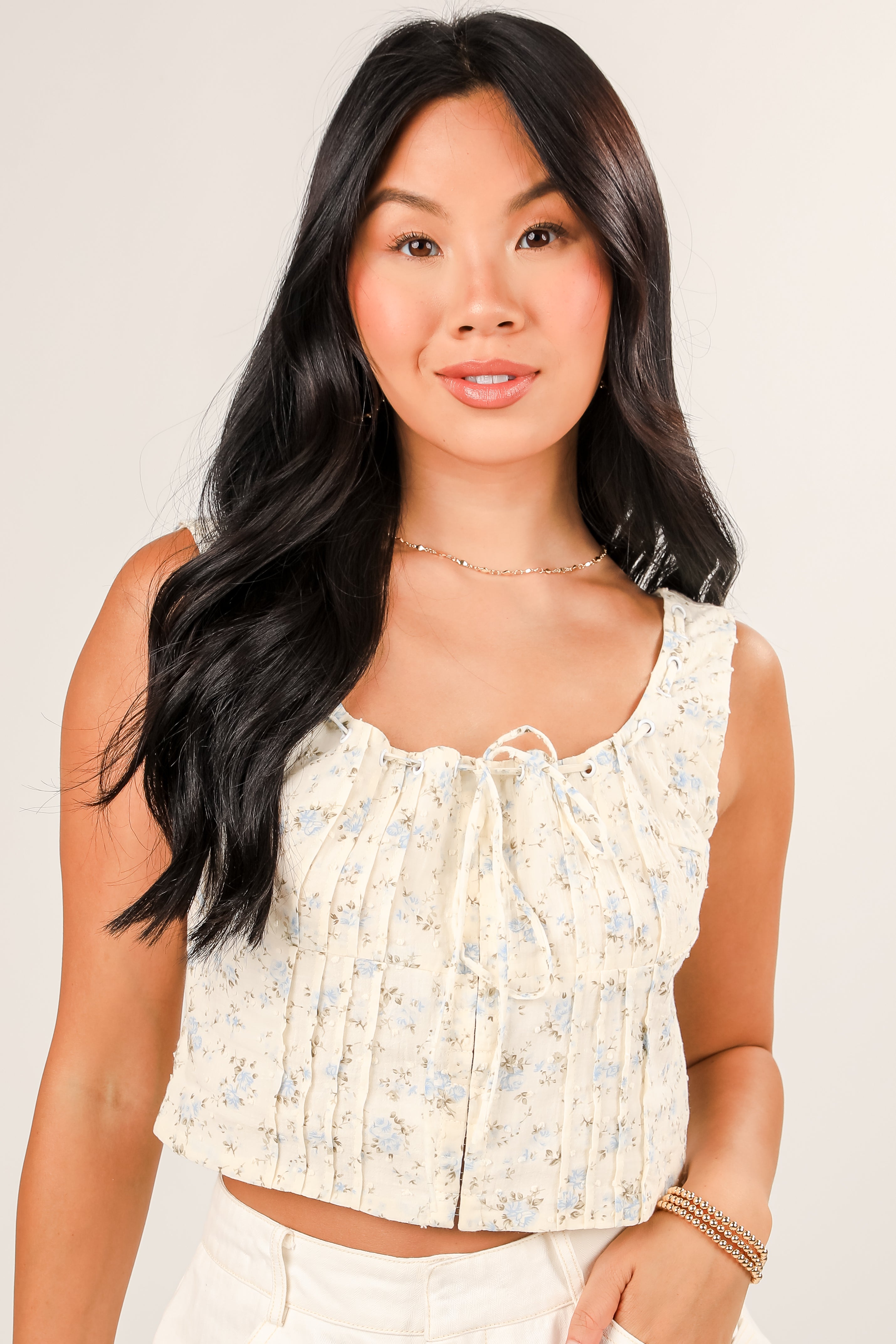 Woman wearing a floral sleeveless top against a plain background