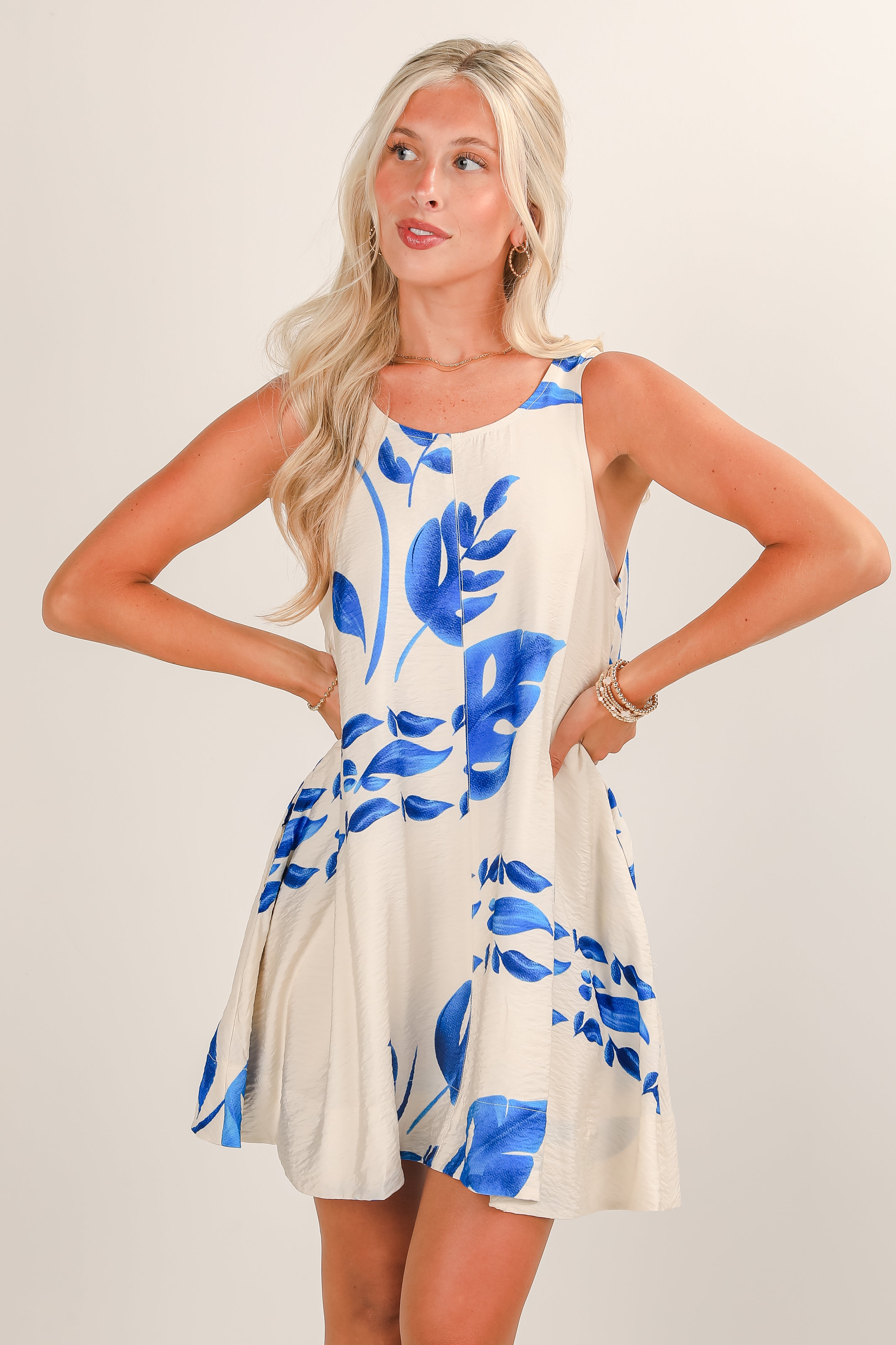 Woman wearing a white dress with blue floral patterns on a plain background