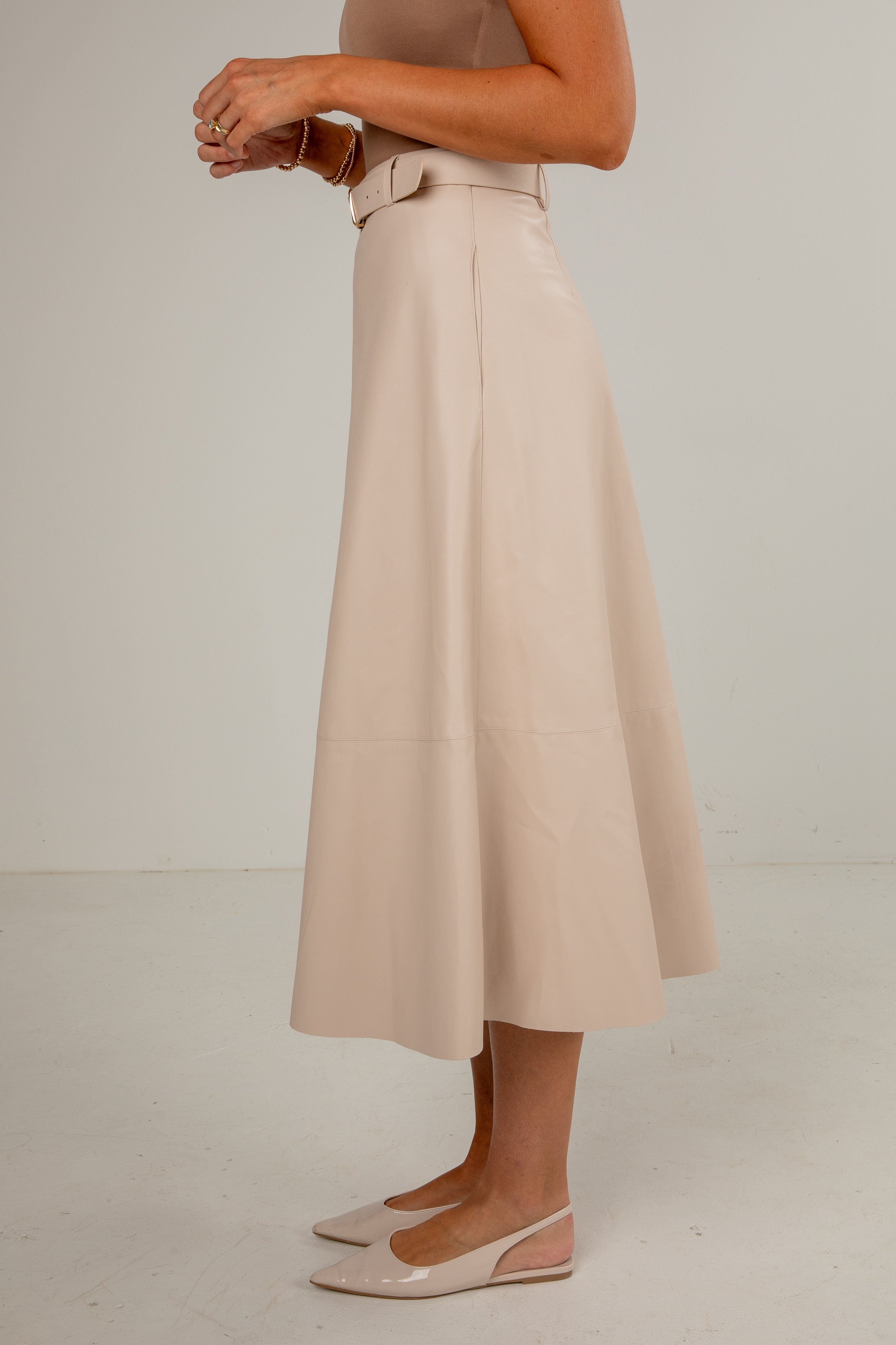 Person wearing a beige skirt with a plain background