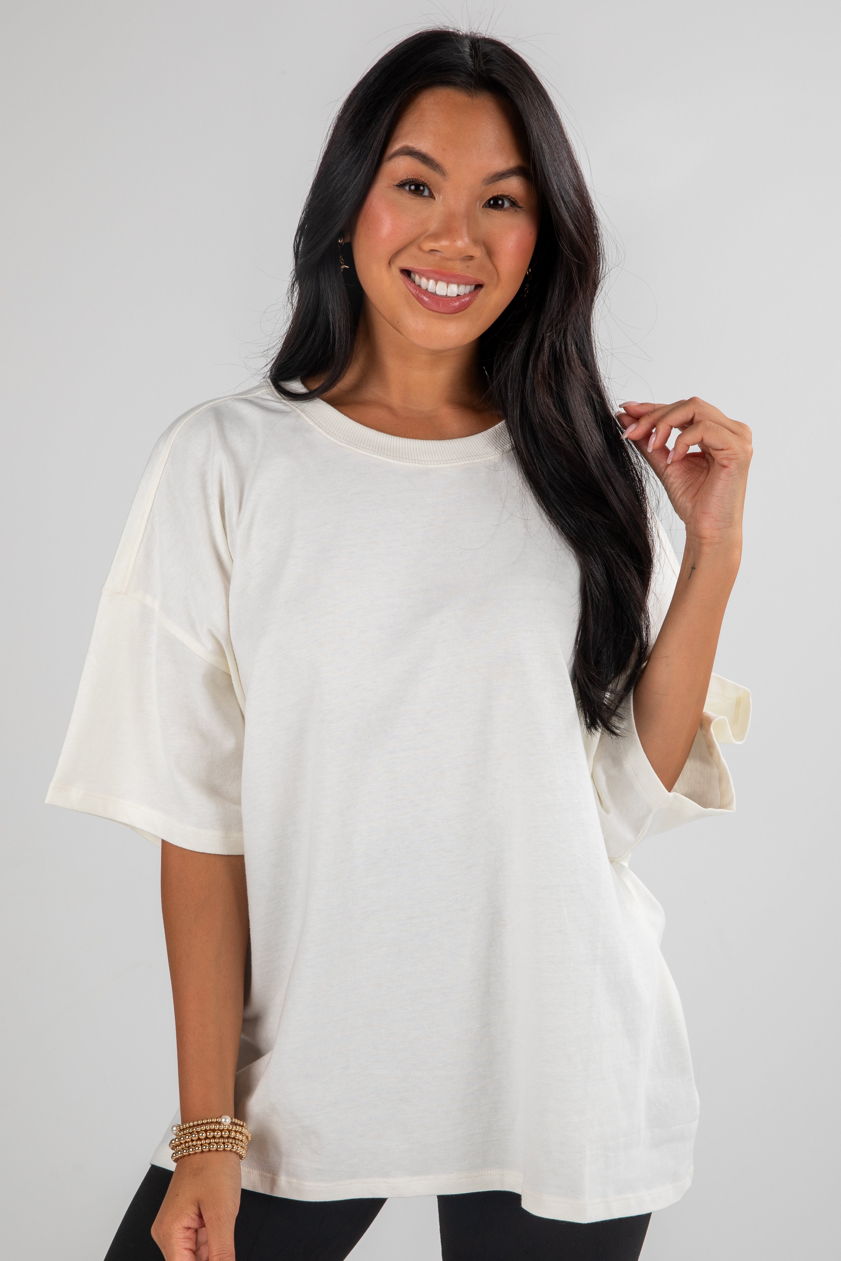 Woman wearing a white oversized t-shirt against a plain background