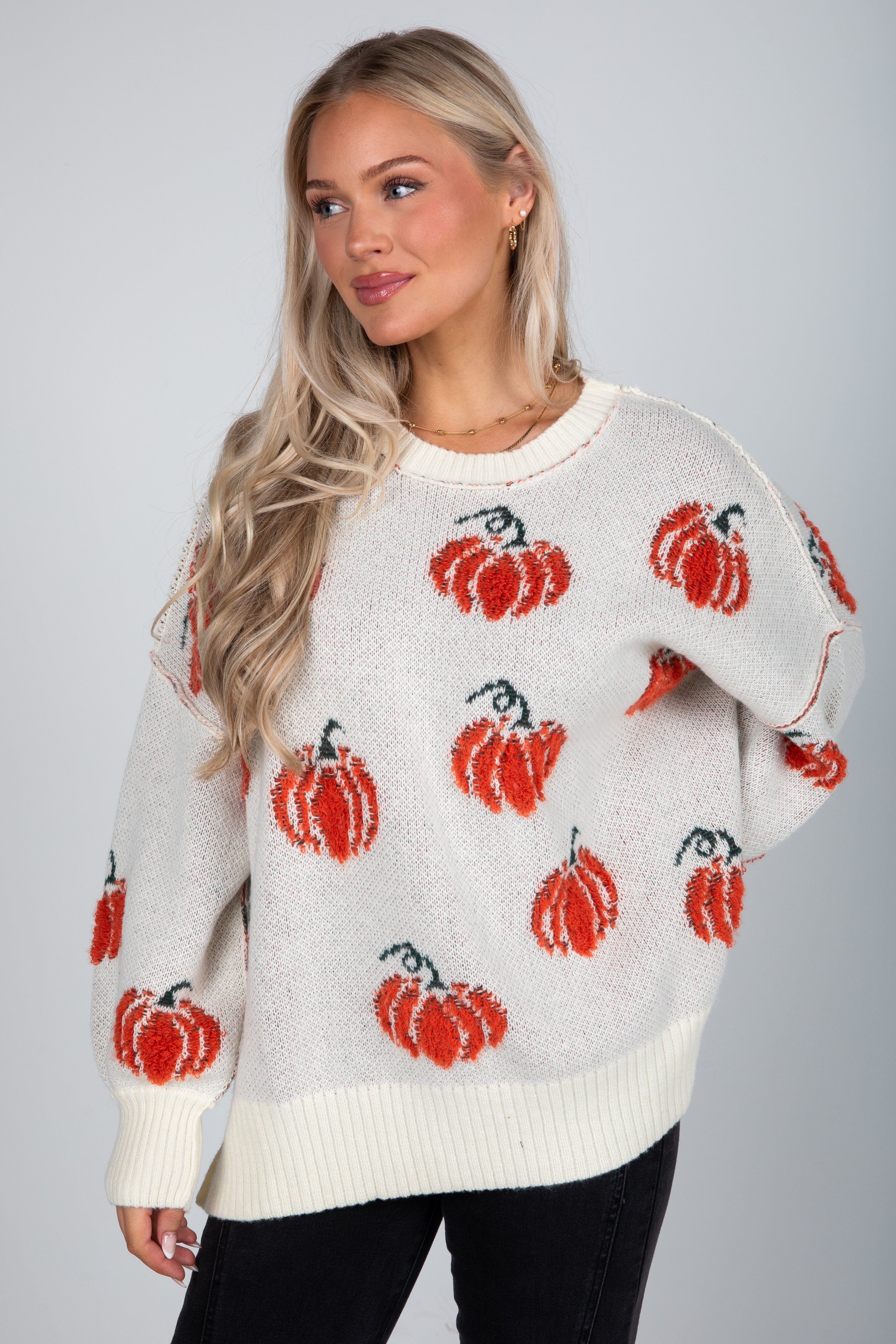 Woman wearing a sweater with red pumpkin patterns on a plain background