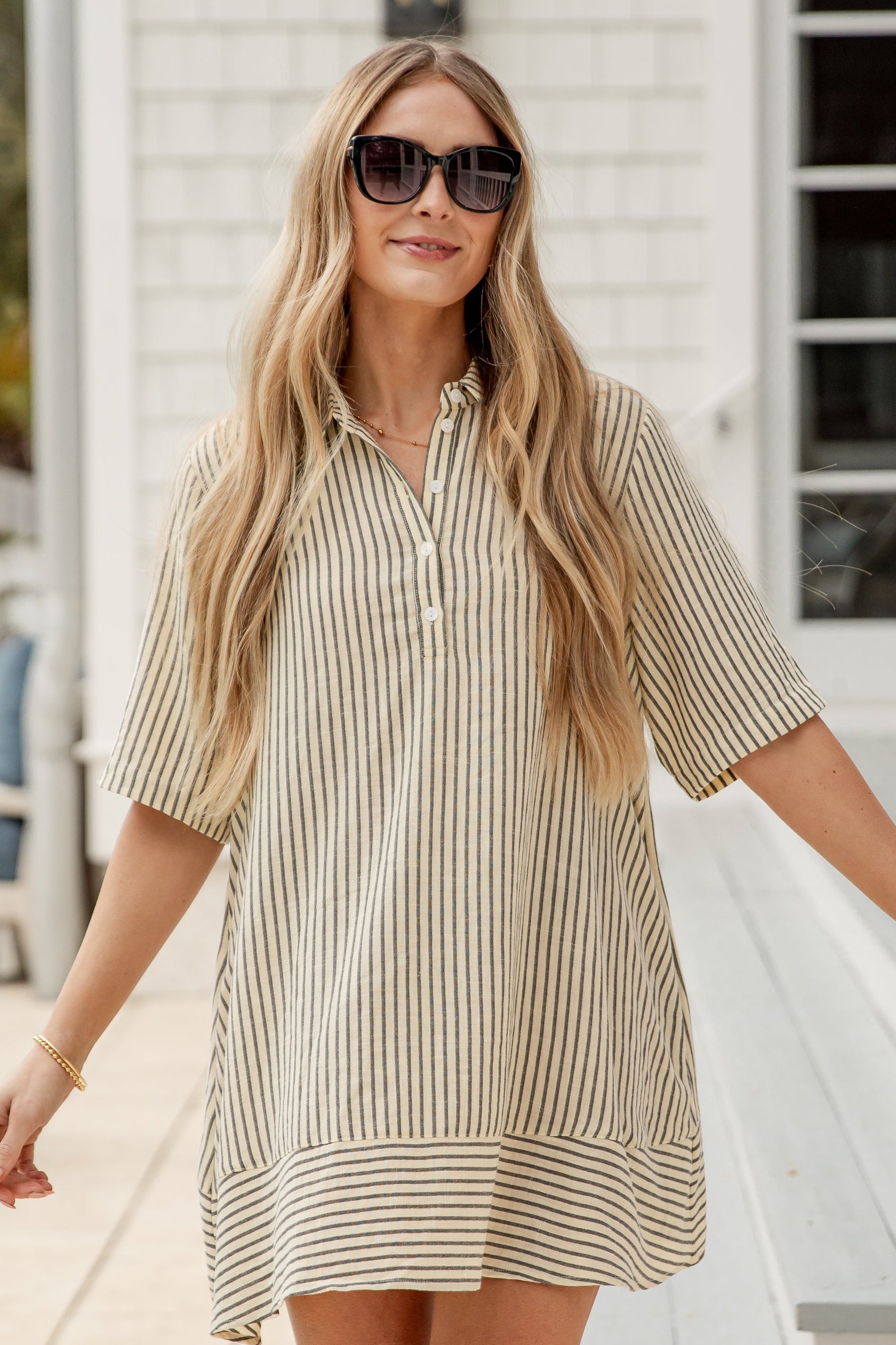 Woman wearing a striped dress standing on a wooden deck.