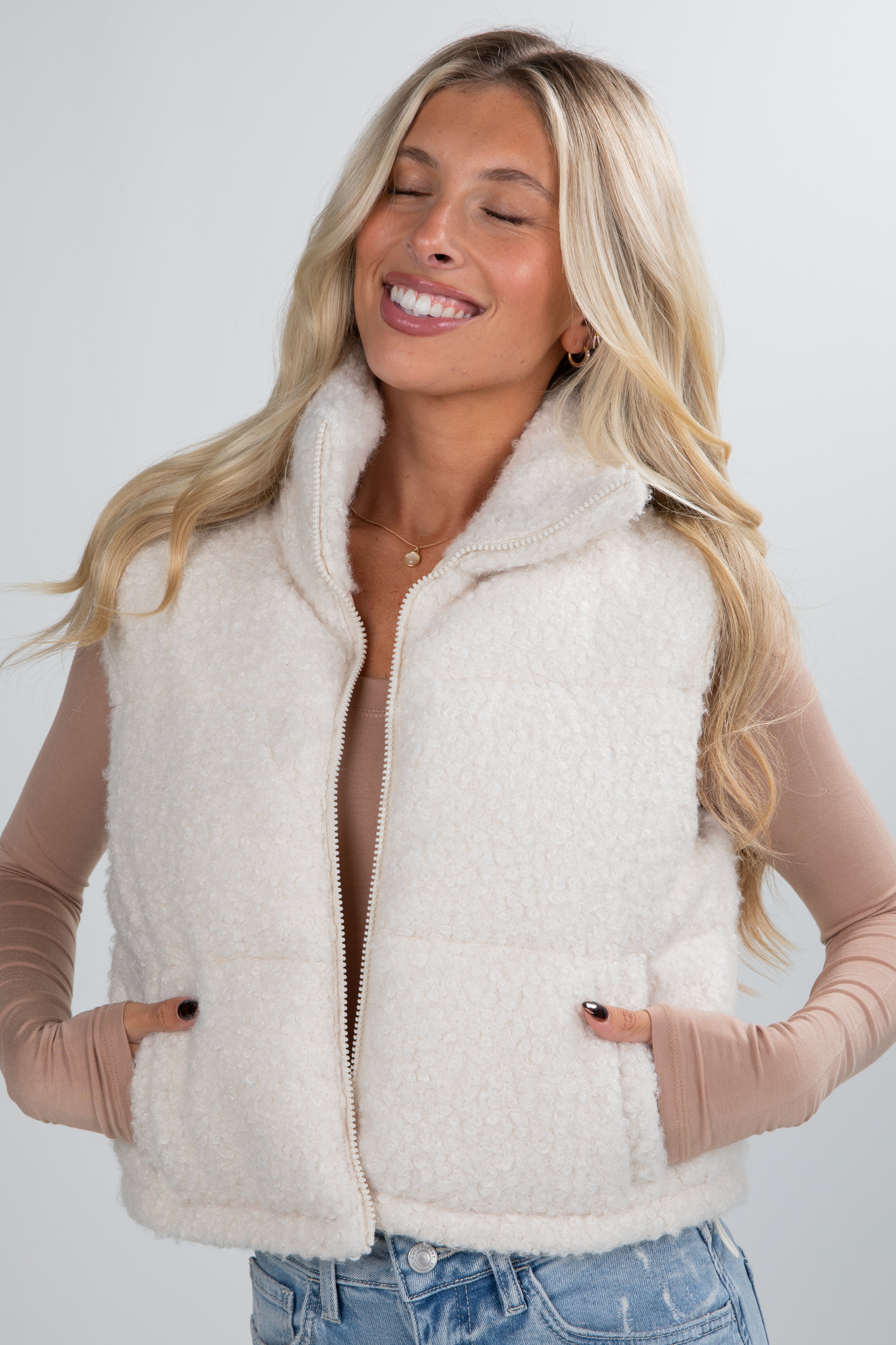 Woman wearing a cream-colored fleece vest against a white background