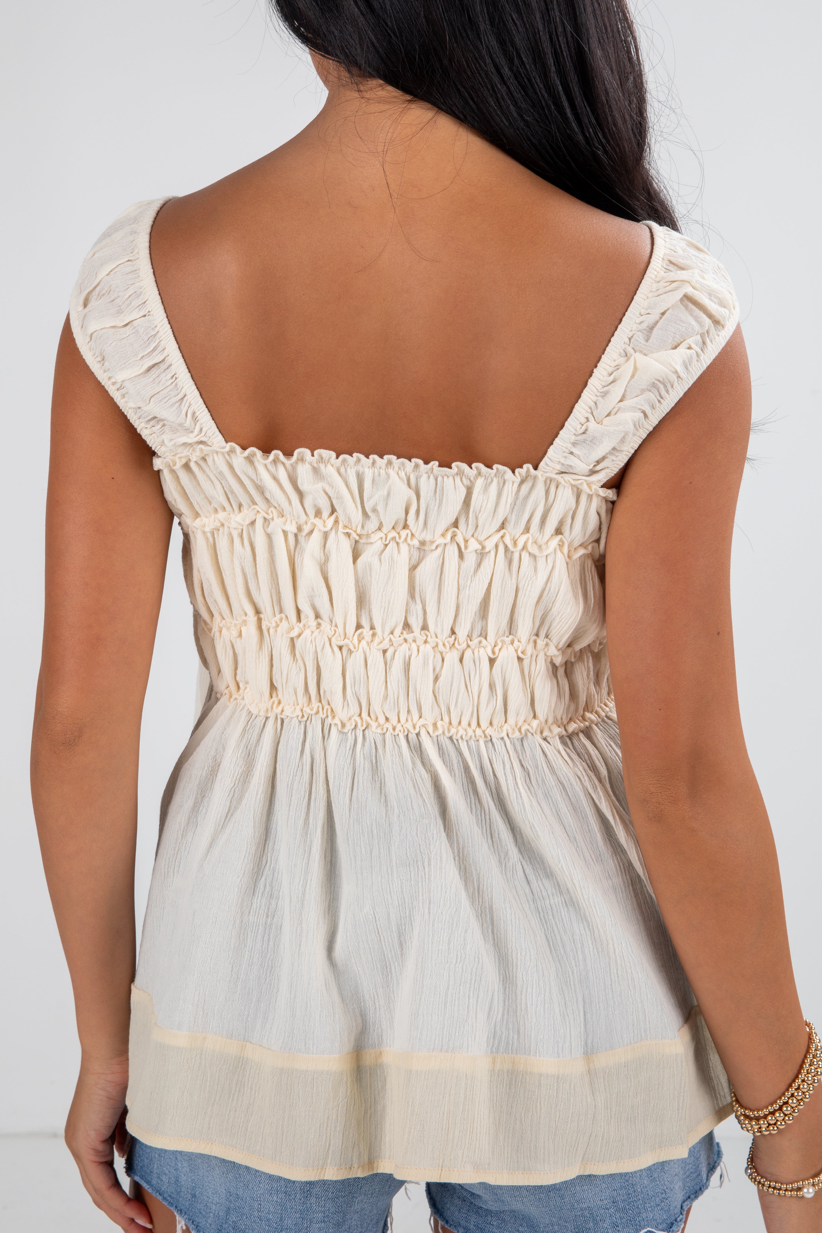 Woman wearing a light-colored top with lace details on a white background