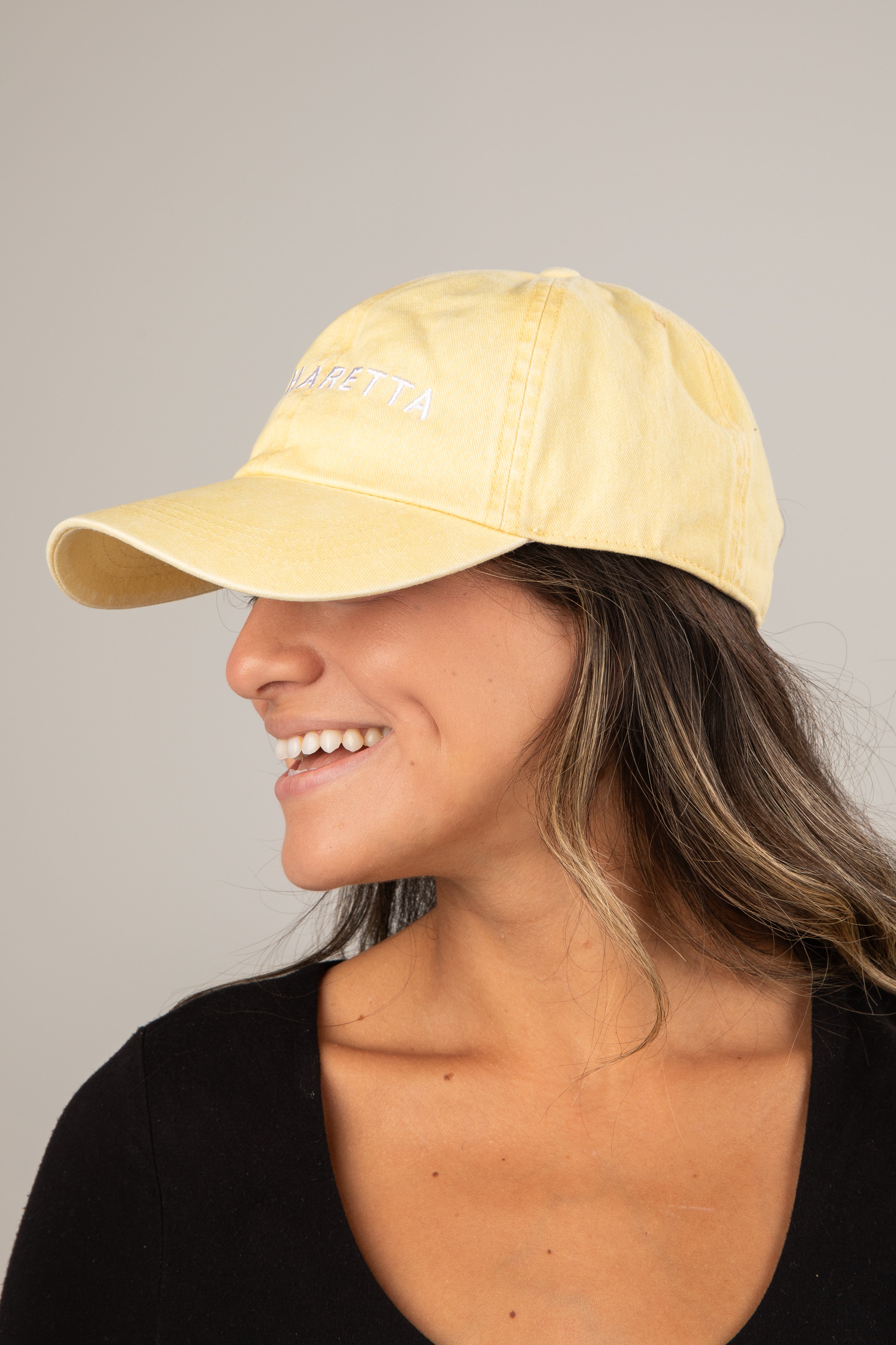 Woman wearing a yellow cap against a gray background