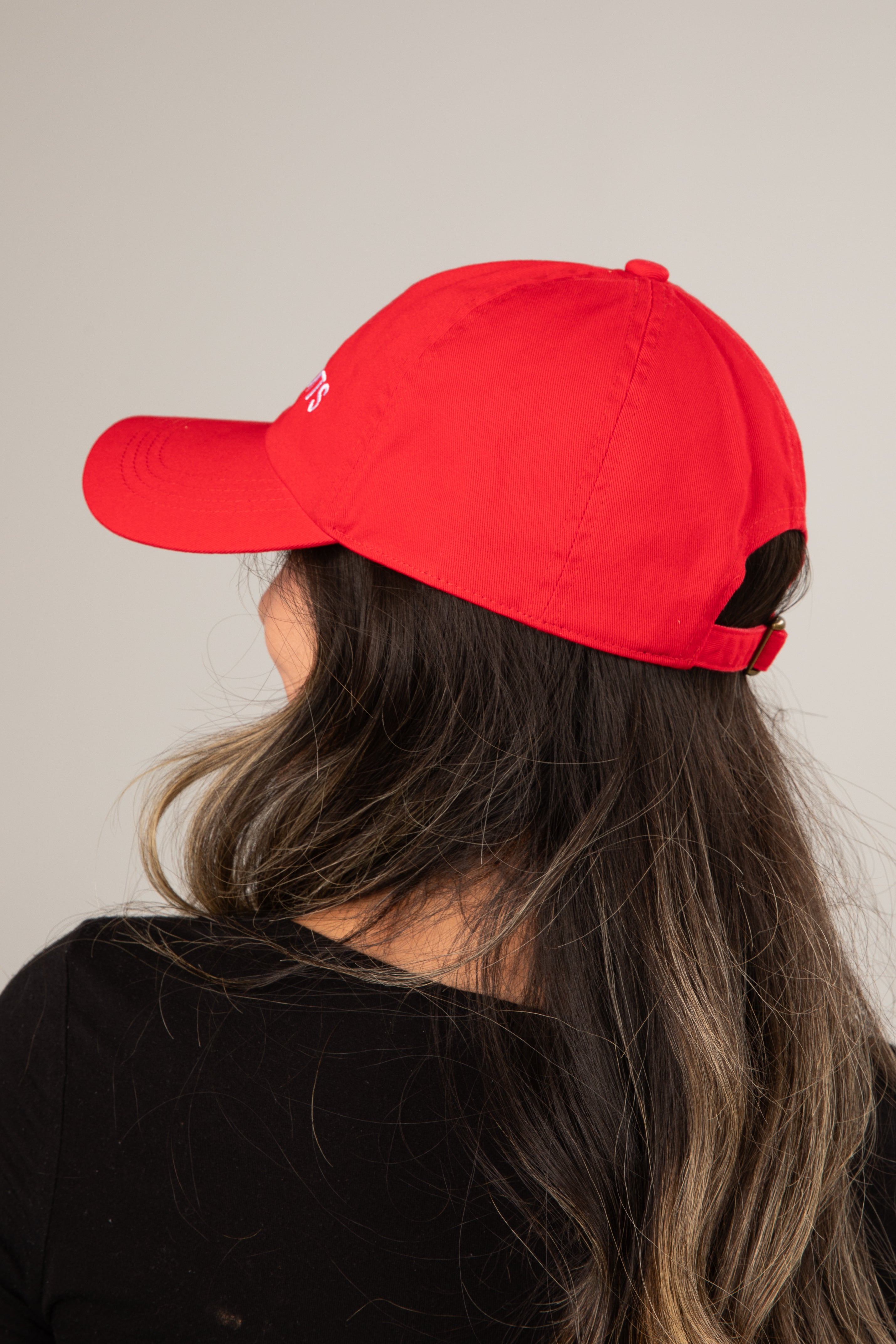 Person wearing a red cap with a logo on a plain background