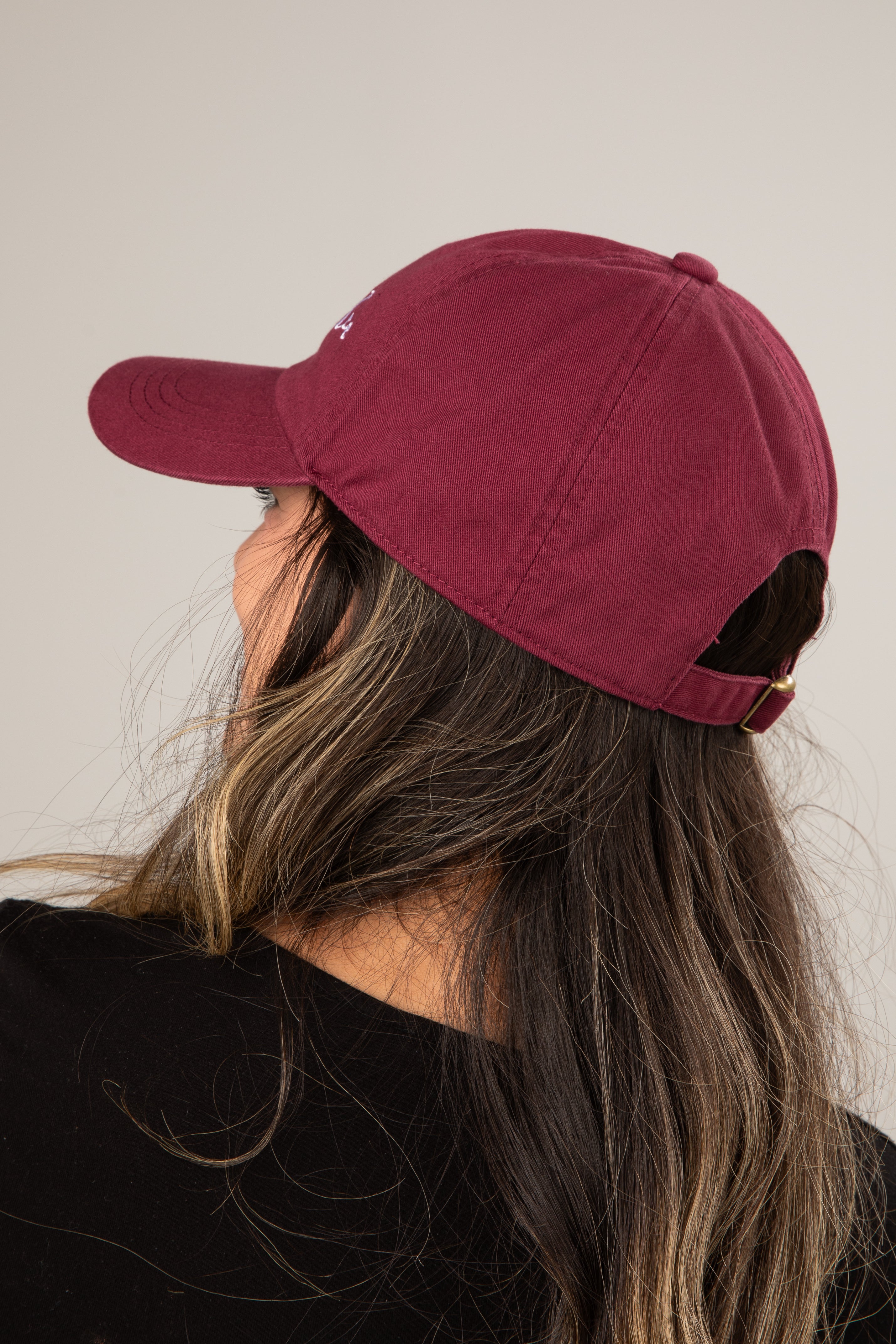 Person wearing a maroon baseball cap with a neutral background