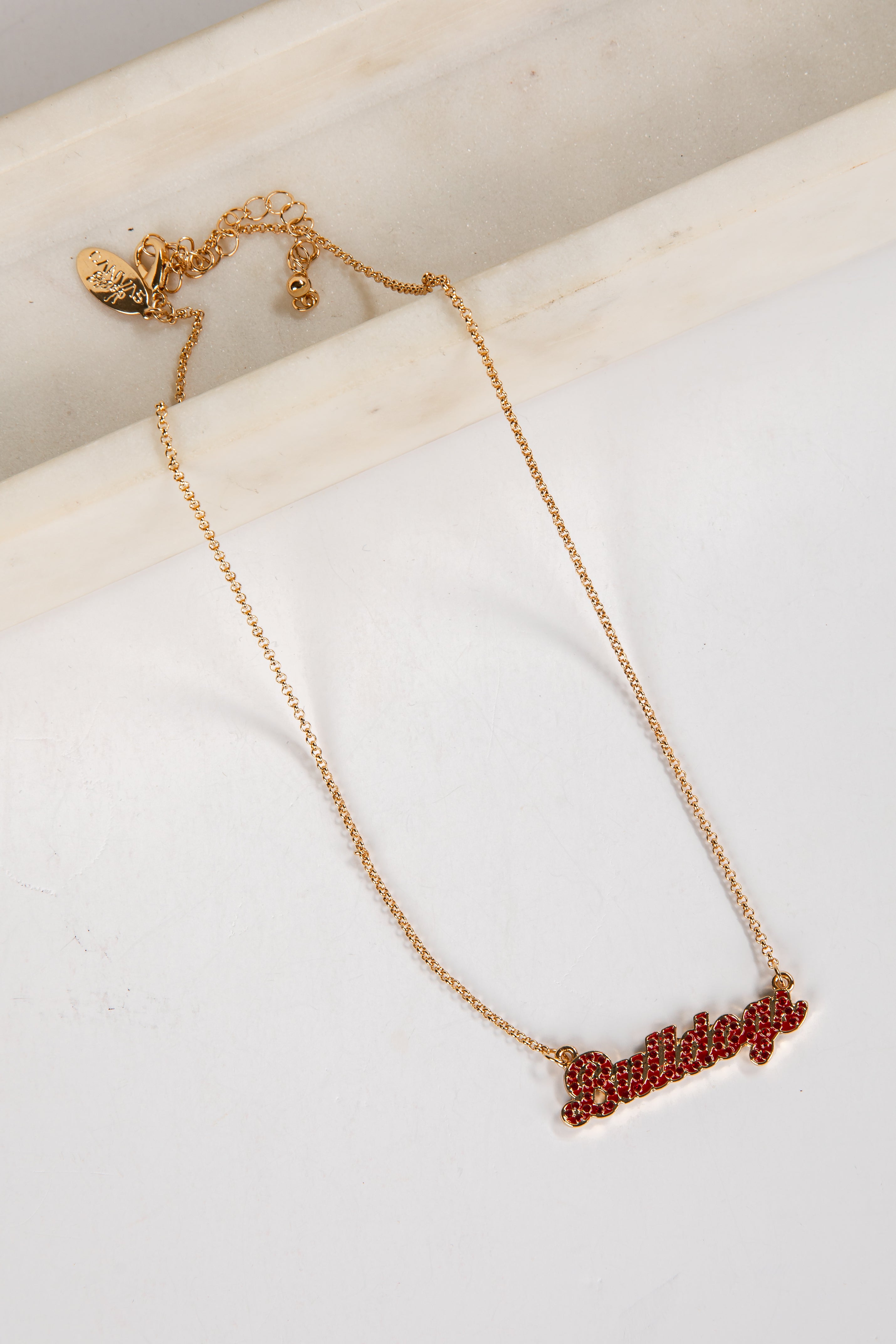 Gold necklace with red stones on a white surface