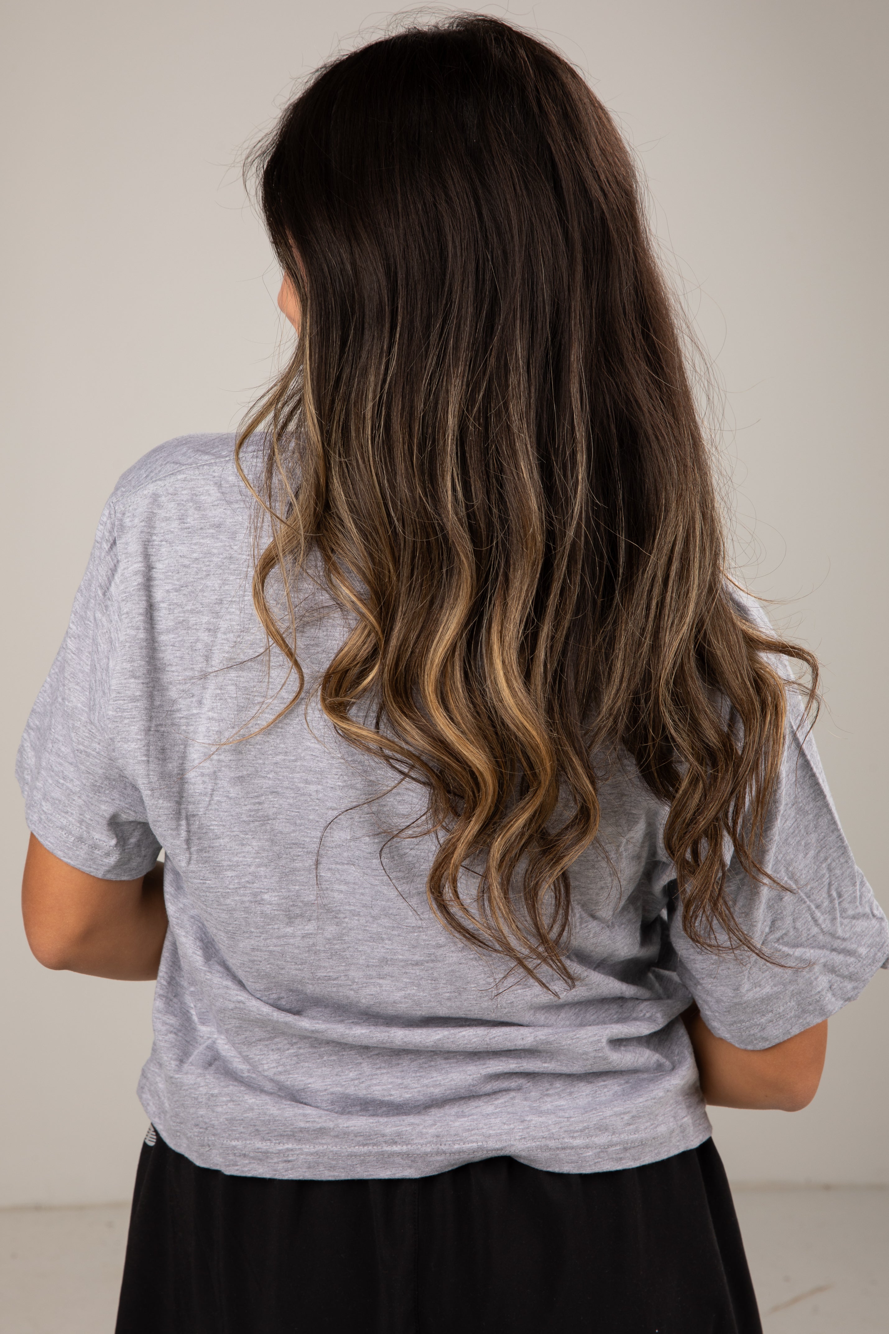 Person wearing a gray t-shirt with long, wavy hair