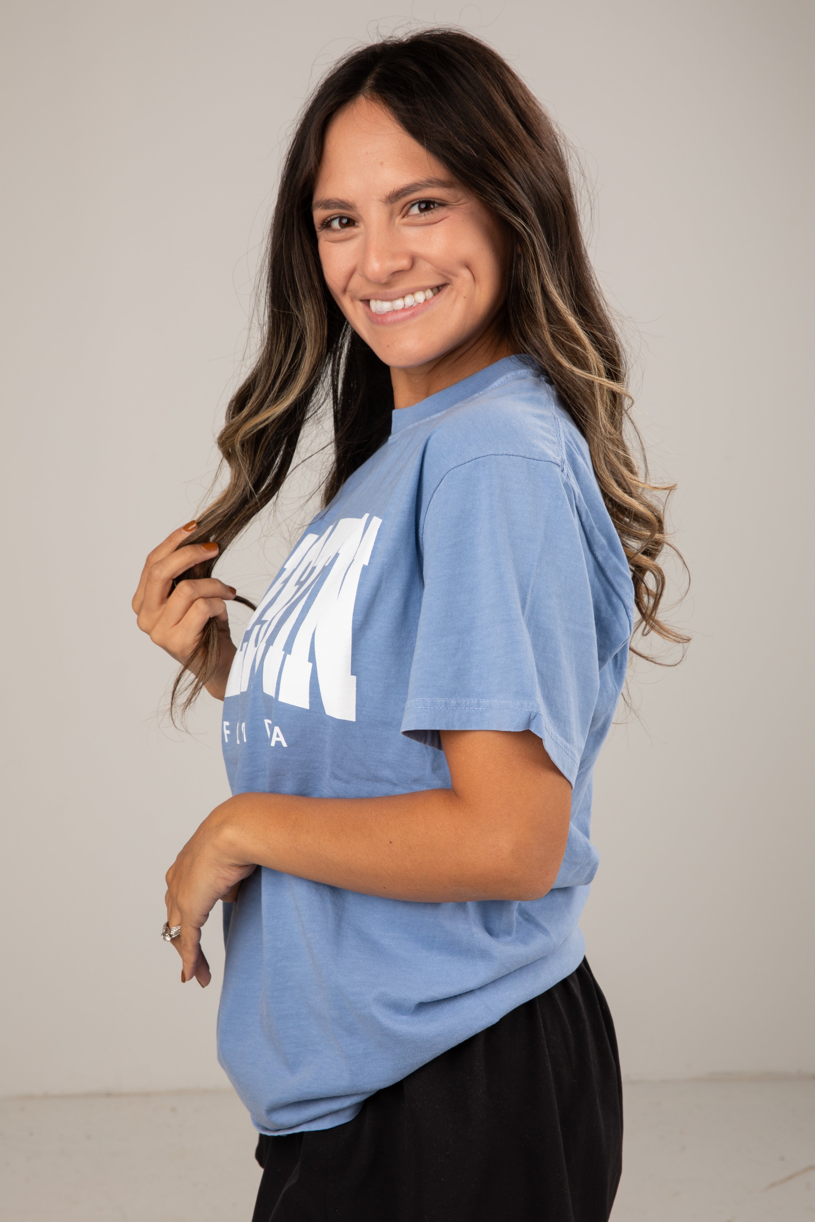 Woman wearing a blue t-shirt with a logo on a plain background