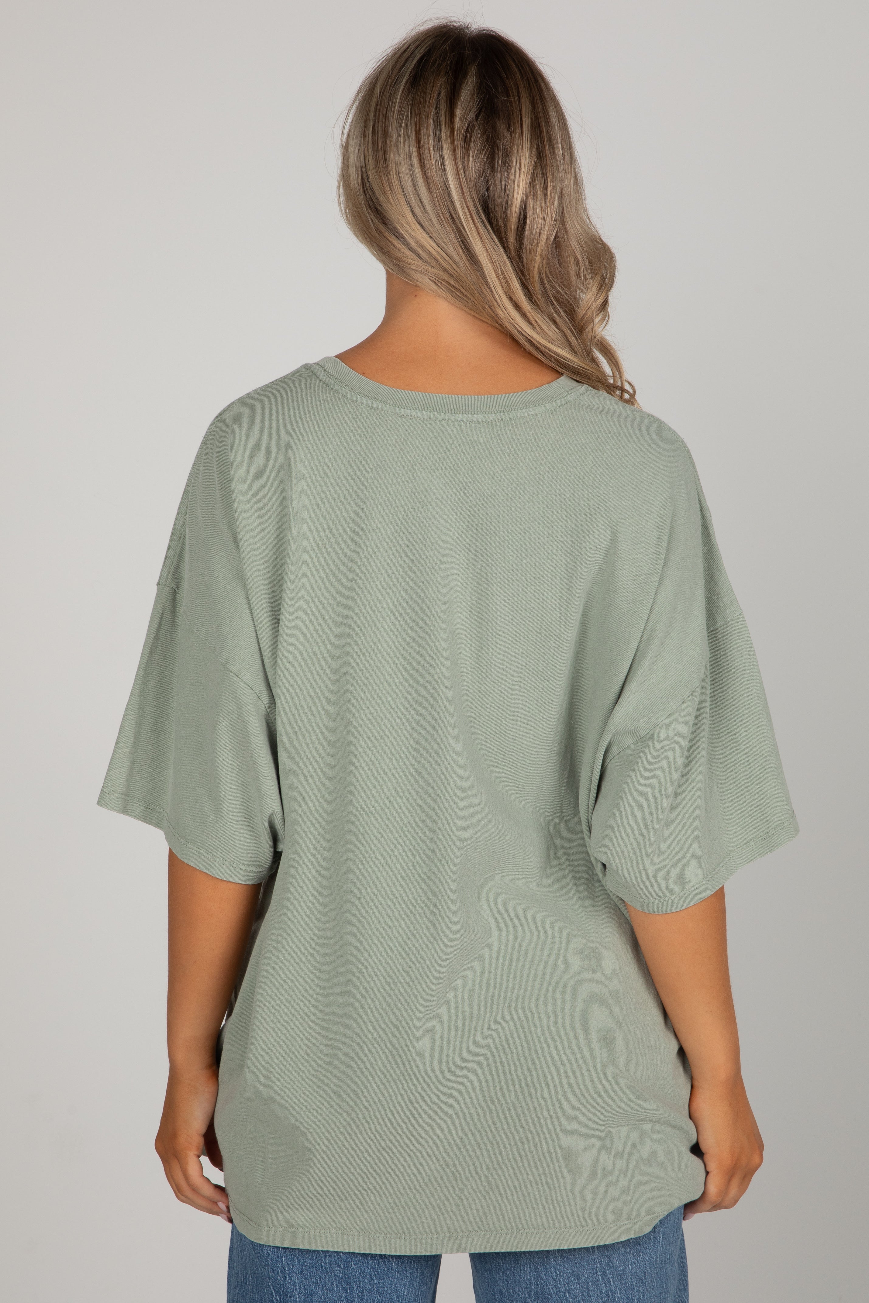 Person wearing a green oversized t-shirt on a plain background