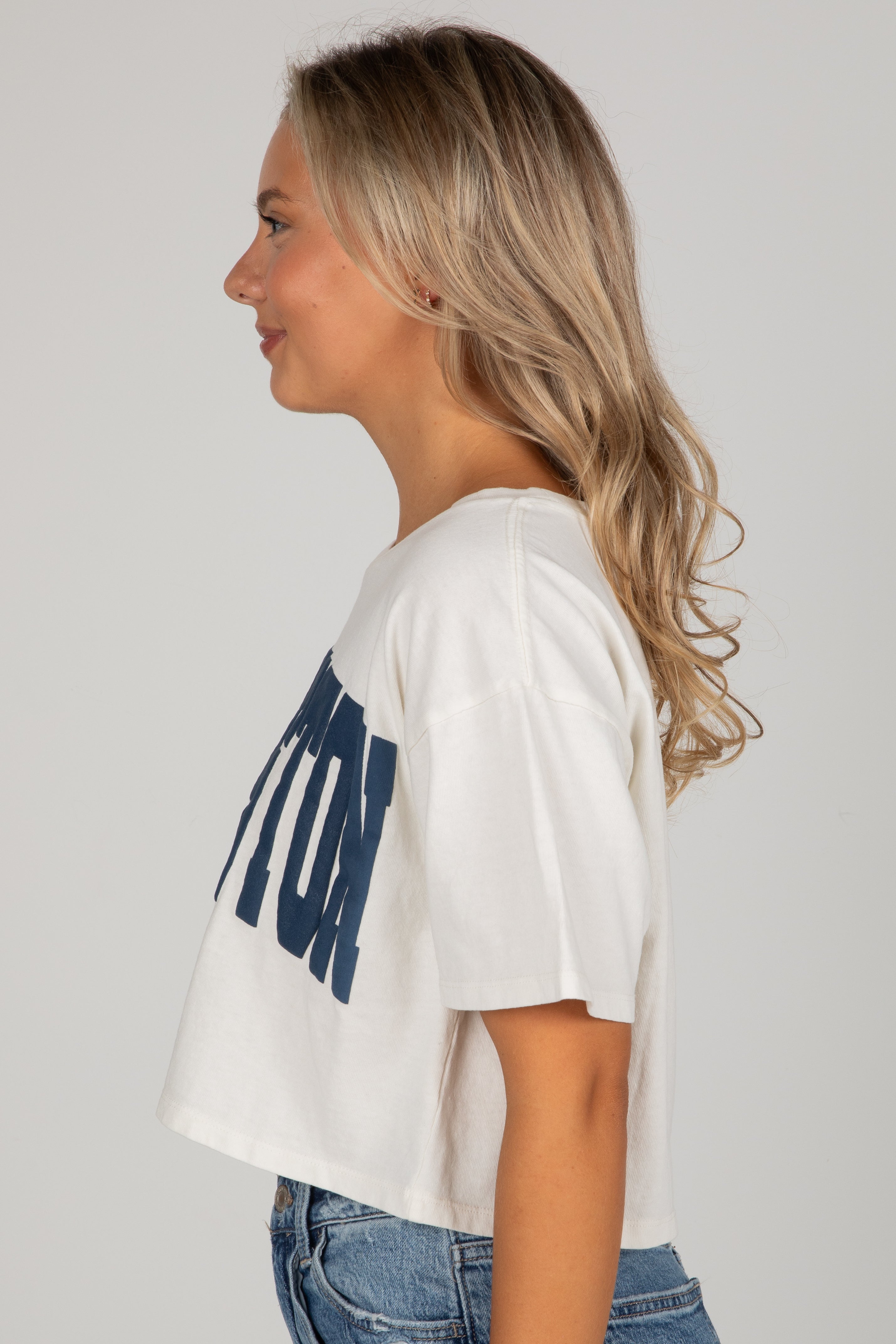 Woman wearing a white t-shirt with blue text on a plain background