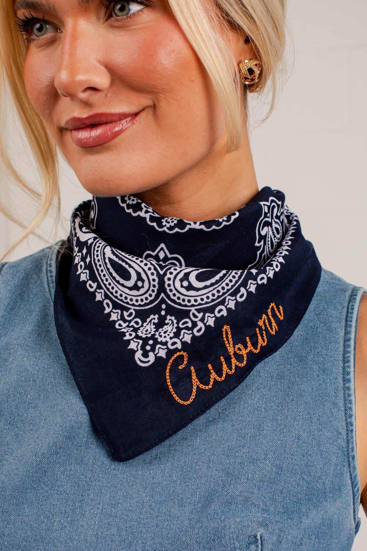 A close-up of a woman wearing a navy blue bandana with a white paisley pattern and the word &