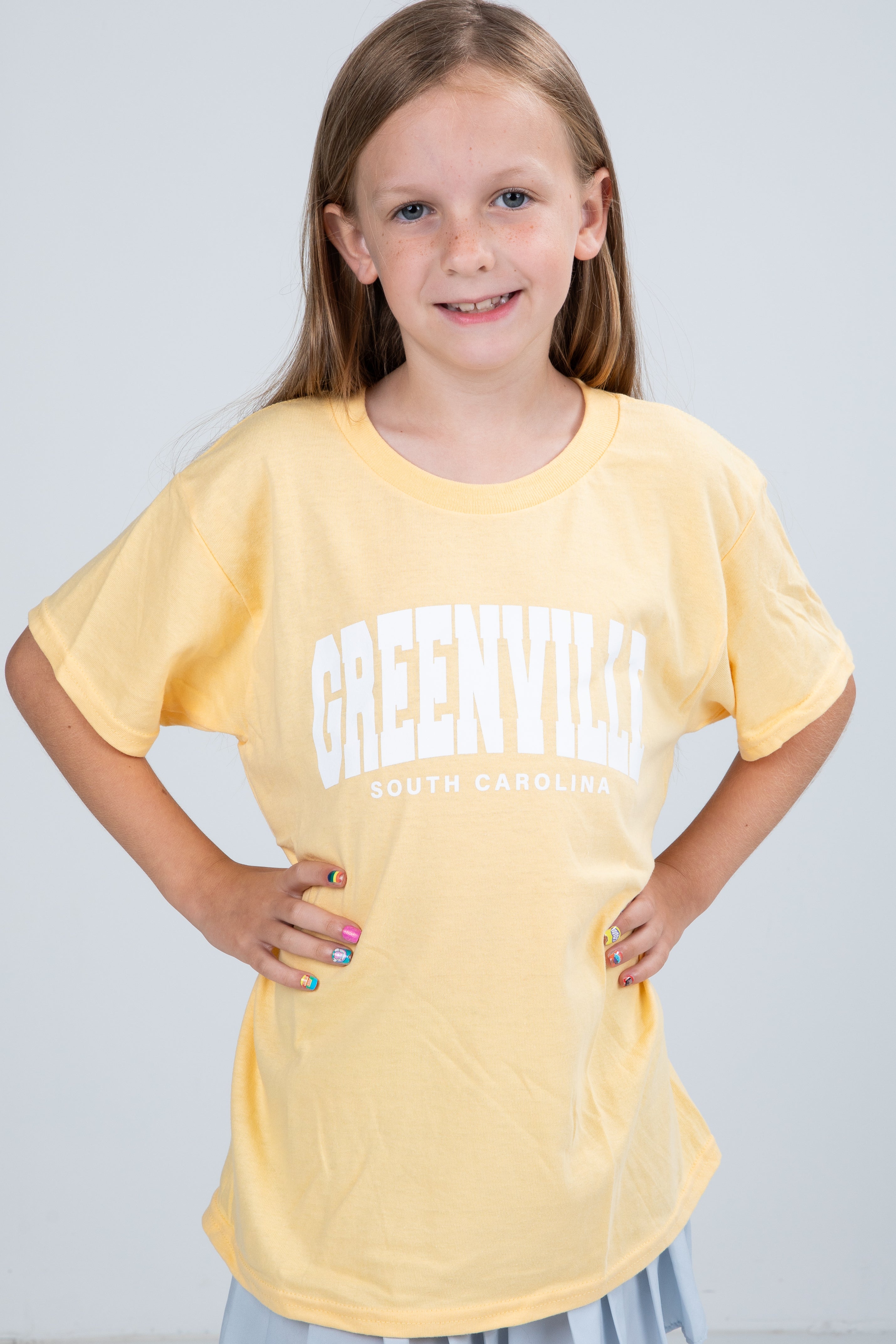 Young girl wearing a yellow t-shirt with &