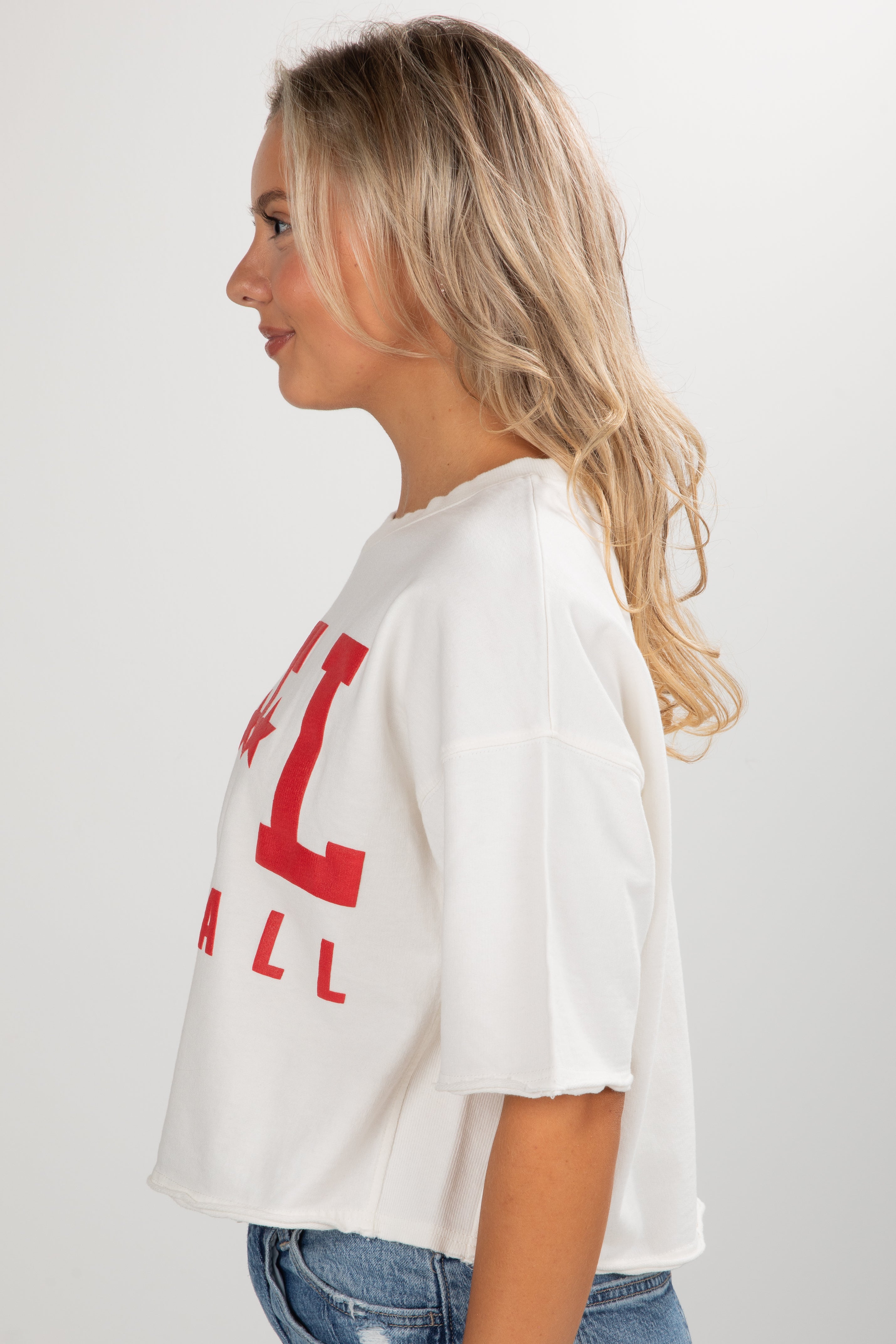 Woman wearing a white t-shirt with red text on a plain background